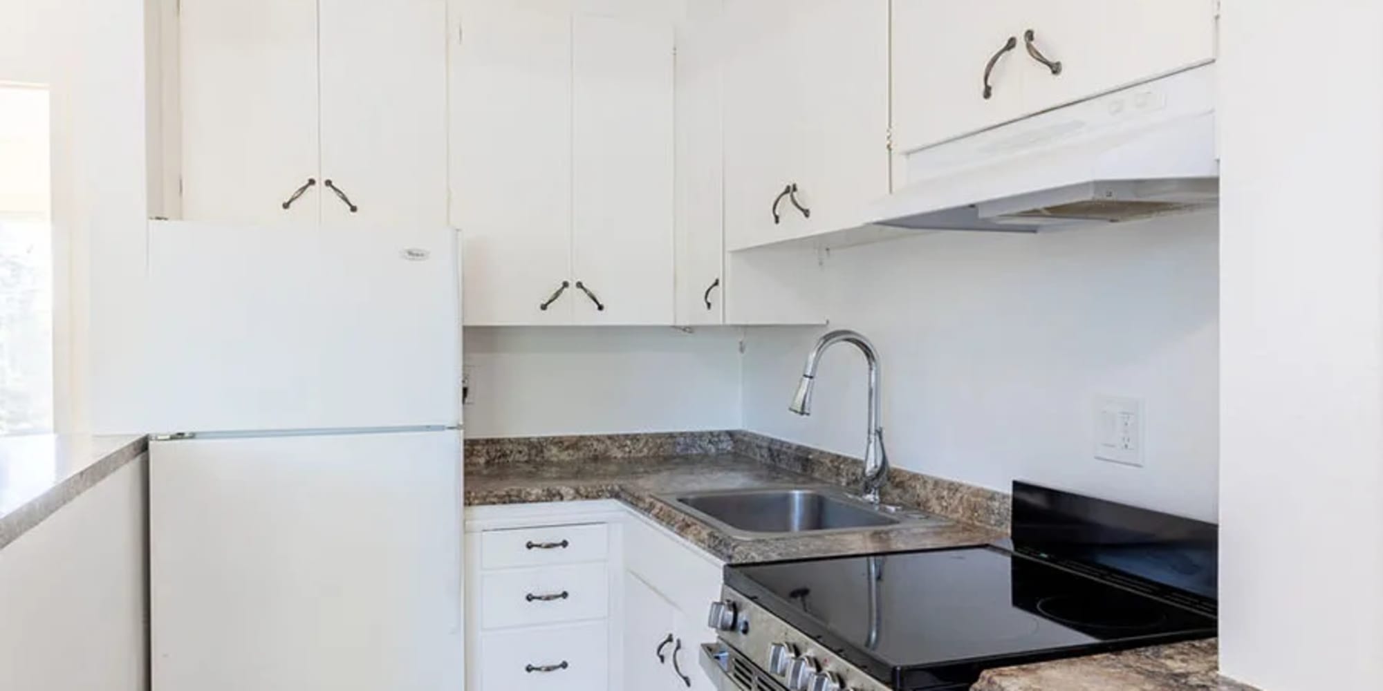 A glass top stove and white cabinets in an apartment kitchen at Silverado Gardens in Napa, California