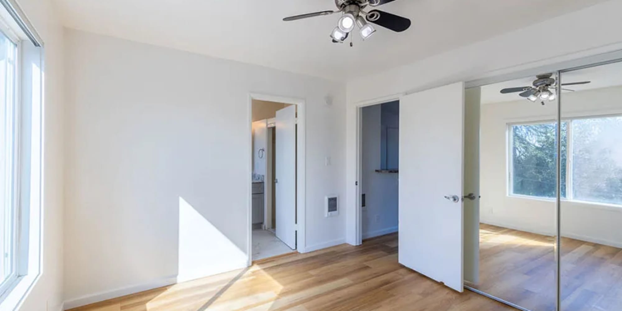 An apartment bedroom with a ceiling fan and mirrored closet doors at Silverado Gardens in Napa, California