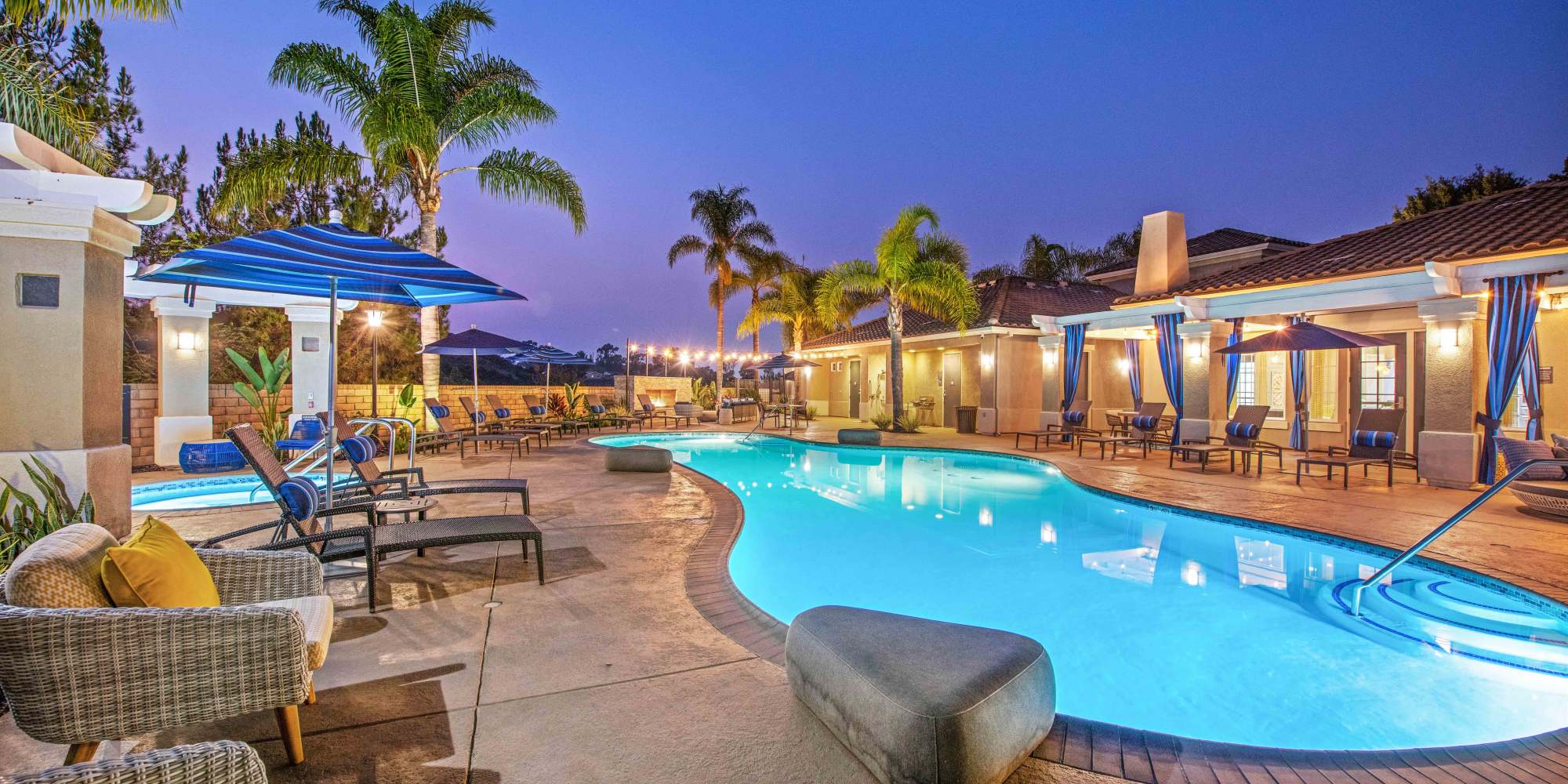 Beautiful night view of a pool area with lounge chairs and palm trees at Sofi Highlands in San Diego, California