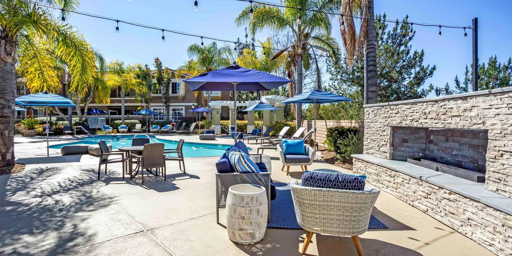 Inviting outdoor lounge area with pool, seating, and tropical palm trees at Sofi Highlands in San Diego, California