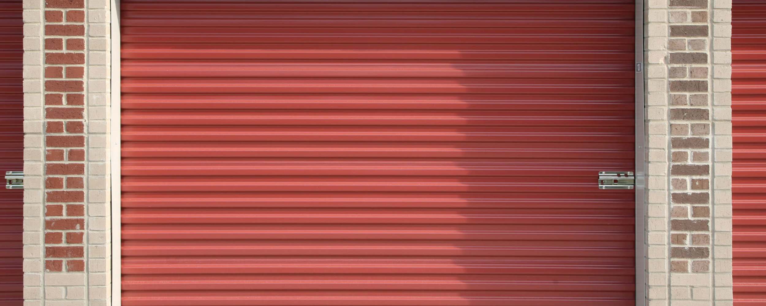 Red metal storage doors with brick columns at Centennial Storage in Bonney Lake, Washington