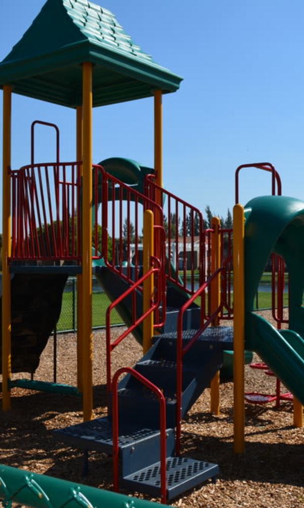 A playground structure with a slide, ladder and a roofed platform at The Abbey At Northlake in Riviera Beach, Florida