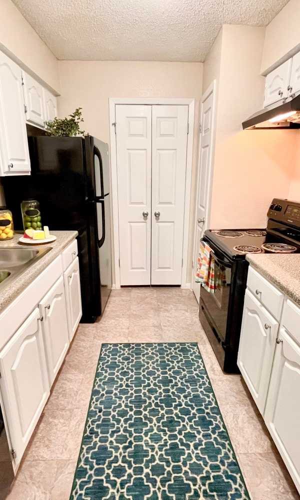Galley-style kitchen with faux granite countertops at The Abbey at Medical Center in San Antonio, Texas