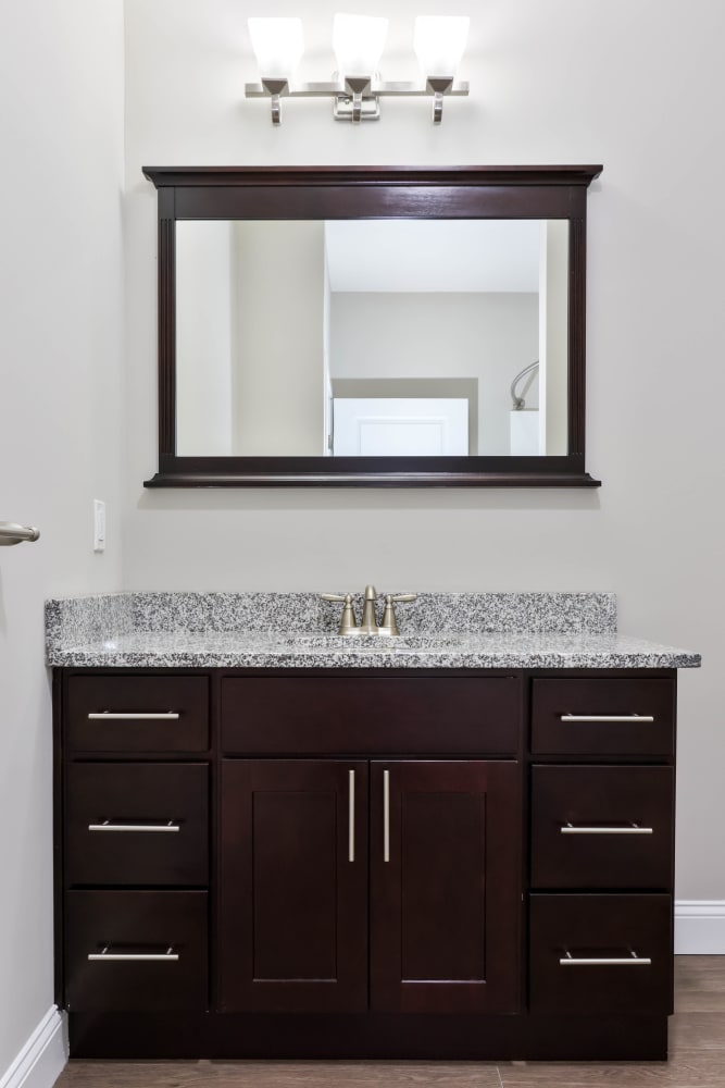 Gorgeous bathroom vanity with wood cabinetry and large mirror in a model home at Five 10 Flats in Bethlehem, Pennsylvania