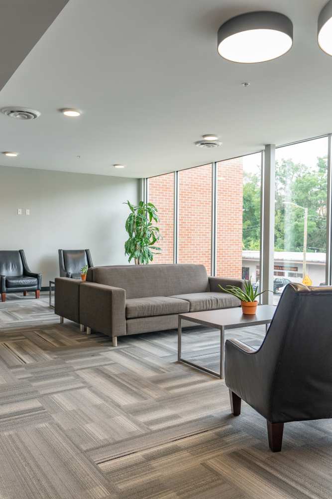 A communal living space with stylish gray couches and chairs at Diamond Place II in Grand Rapids, Michigan