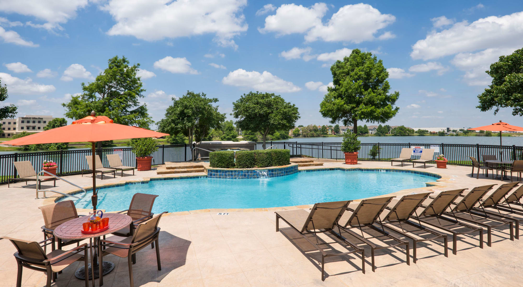 Pool with chairs and lake view at Crescent Cove at Lakepointe 