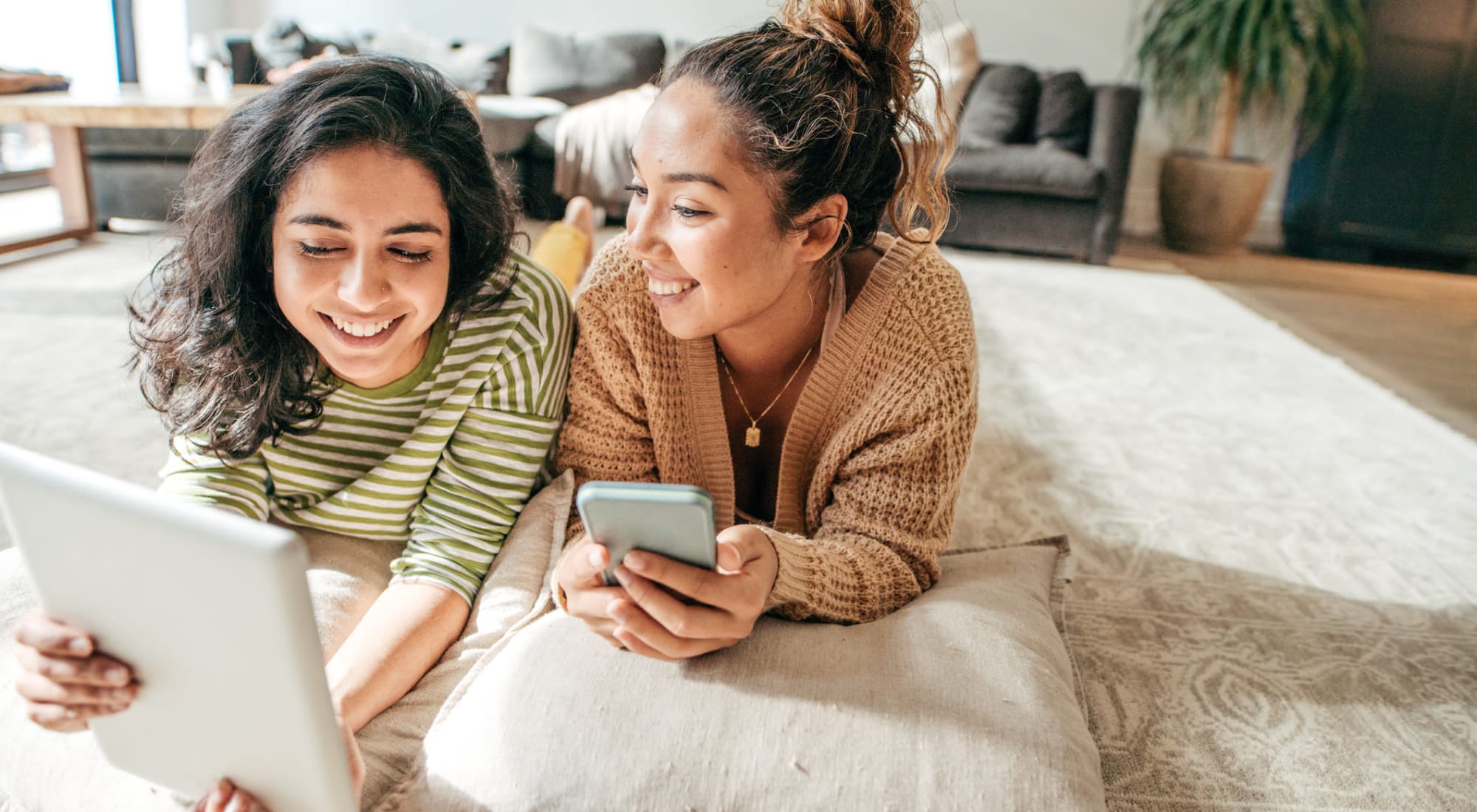 Residents laying on the floor of their new living room looking at their tablet and phone at Cheltenham Station in Philadelphia, Pennsylvania