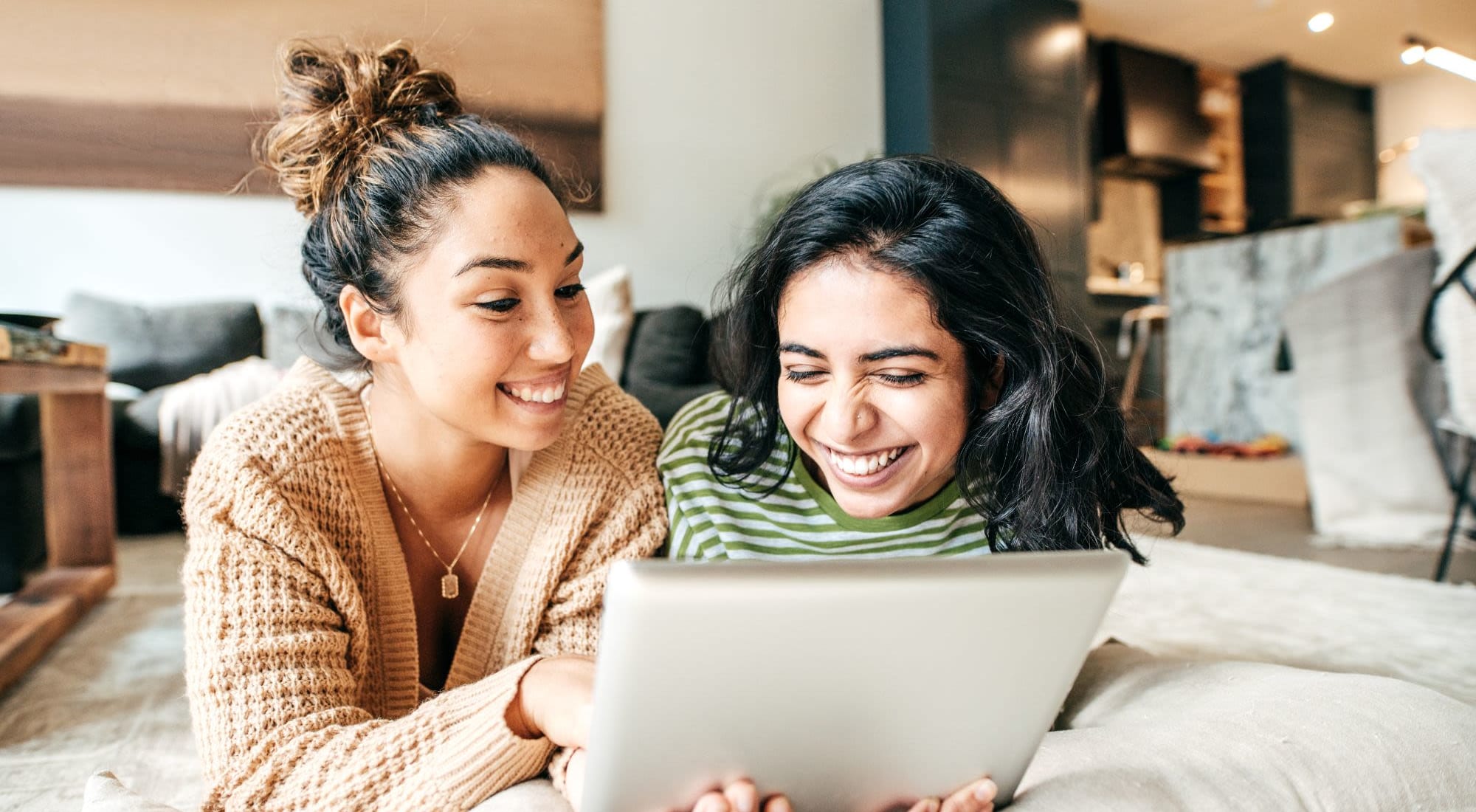 Two Women Smiling and Working on a Laptop Together in an Apartment at 1221 Vallejo Apartments in Novato, California