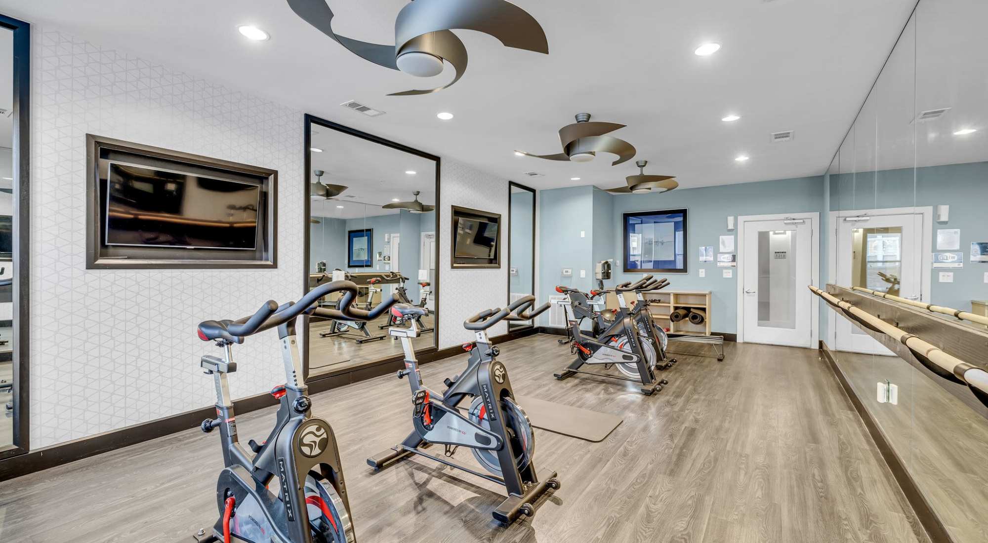 A Fitness Center With Stationary Bikes, Wall Mirrors, And Modern Ceiling Fans. at Artessa in Franklin, Tennessee