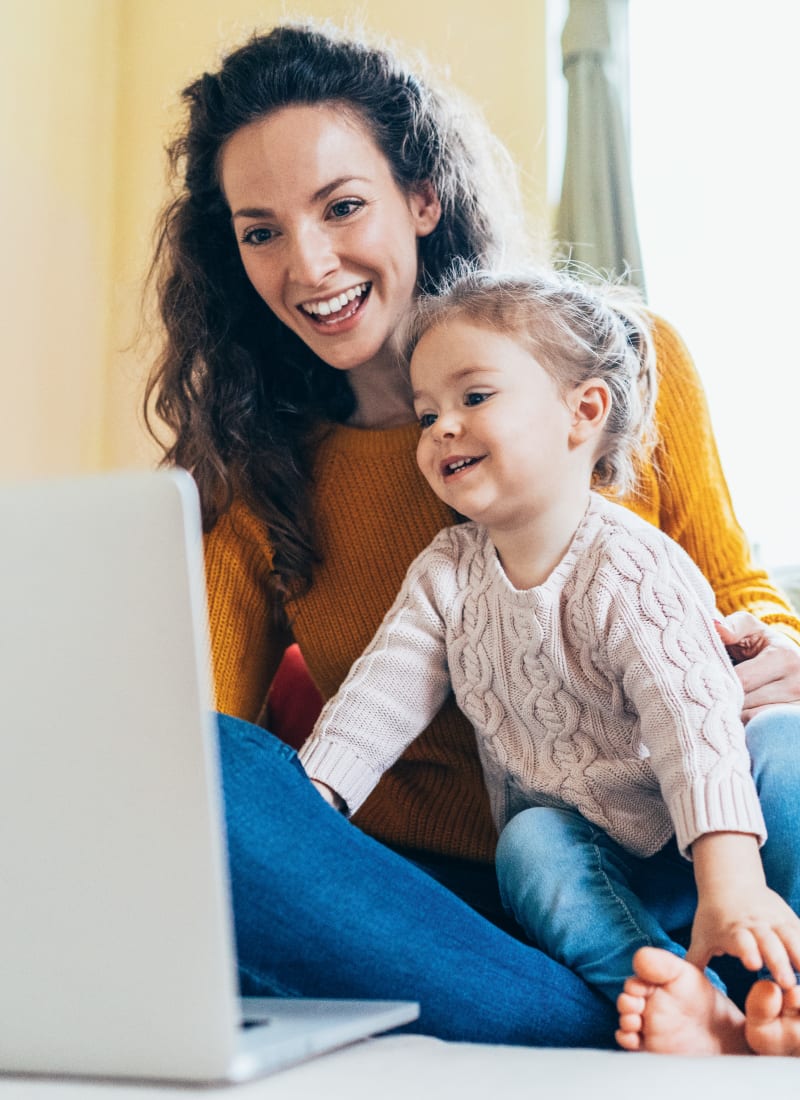 Resident working on computer with daughter on her lap at Marquis at Great Hills in Austin, Texas
