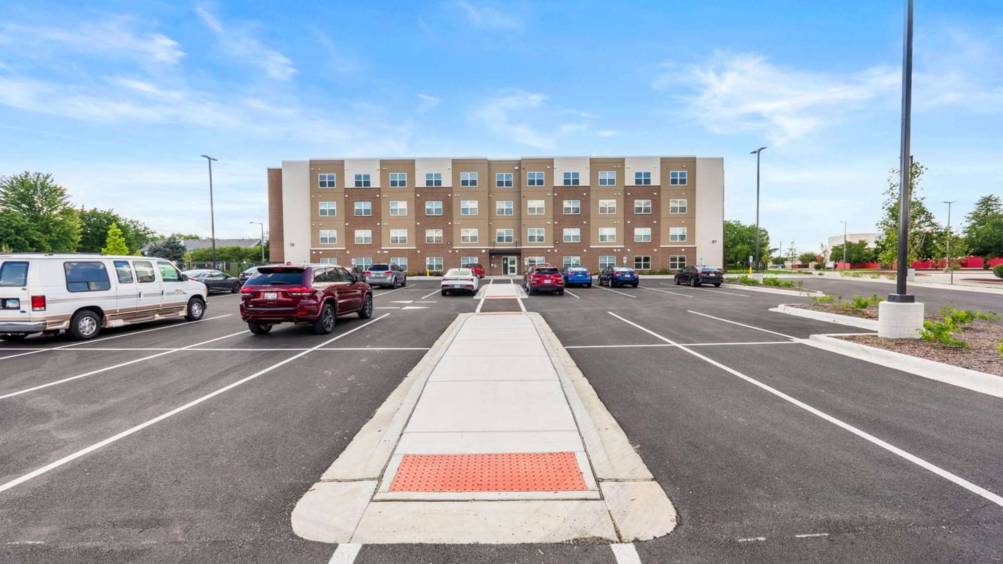 Exterior view of apartment building with car parking at Deville Manor in Oswego, Illinois