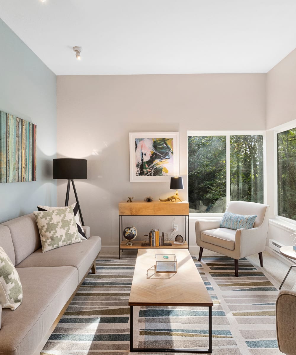 Model home's living area with large bay windows and wooded views at Sofi at Somerset in Bellevue, Washington