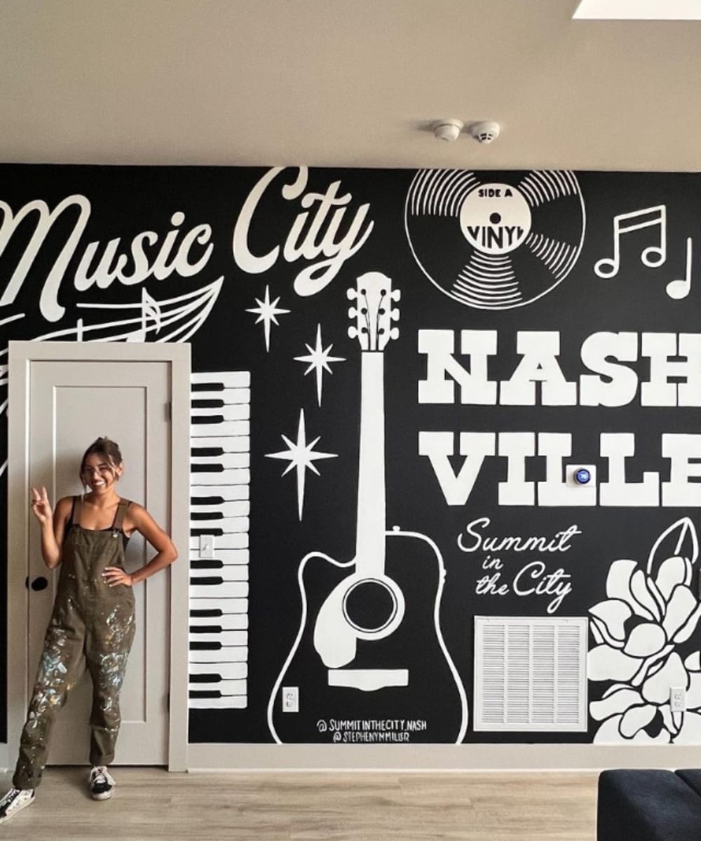 Artist Stepheny Miller standing in front of a Nashville themed mural