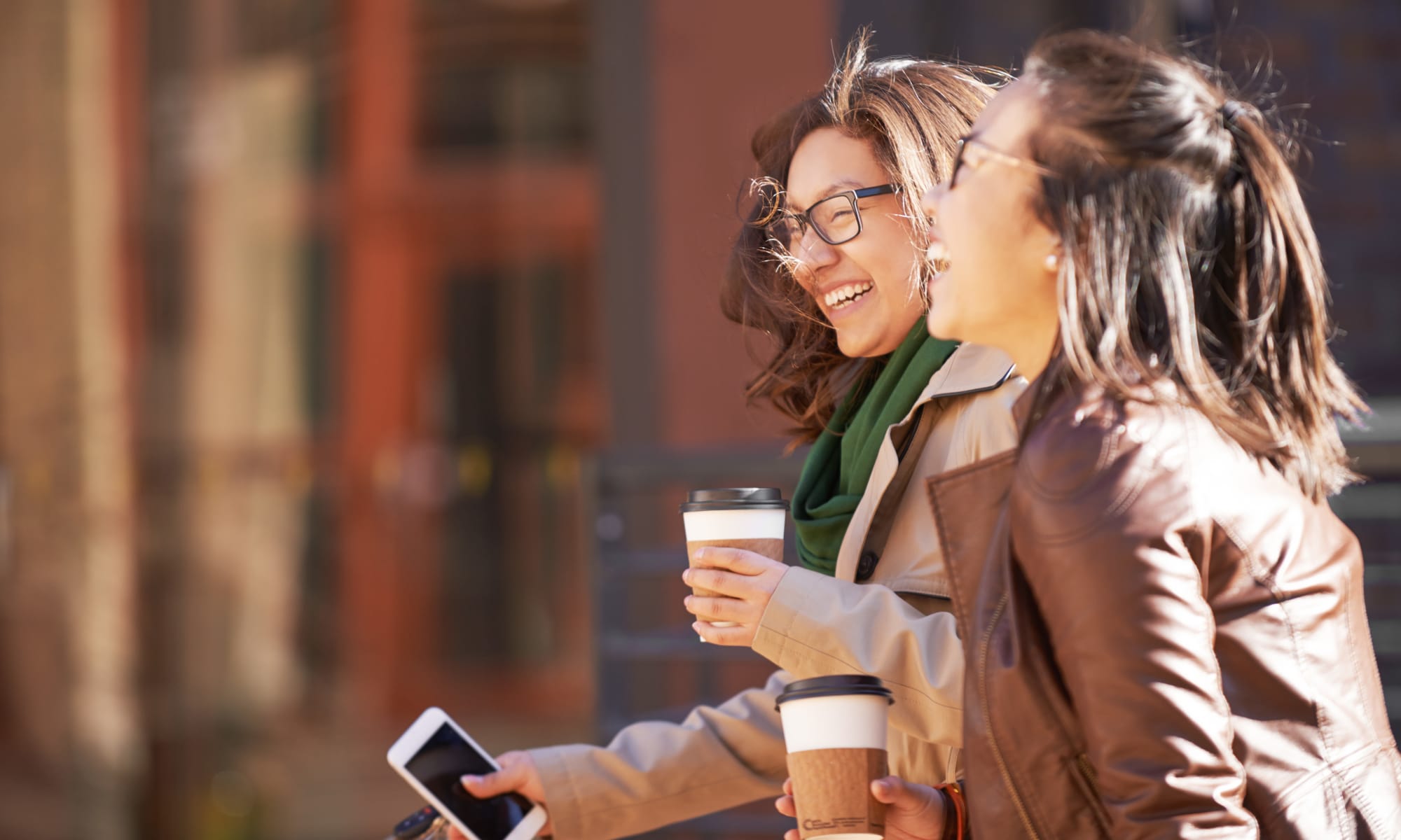 Student friends out enjoying coffee while on a walk in the city near Uptown Ann Arbor in Ann Arbor, Michigan
