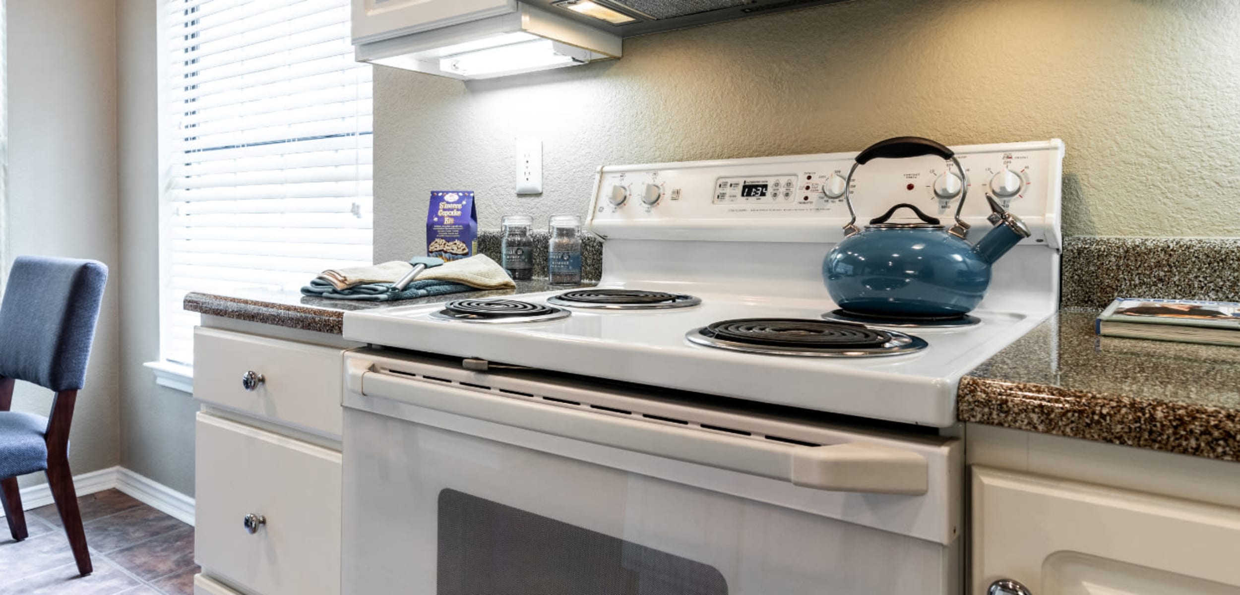 Bright kitchen with laminate counters, white cabinets, and white appliances at Marquis at Waterview in Richardson, Texas