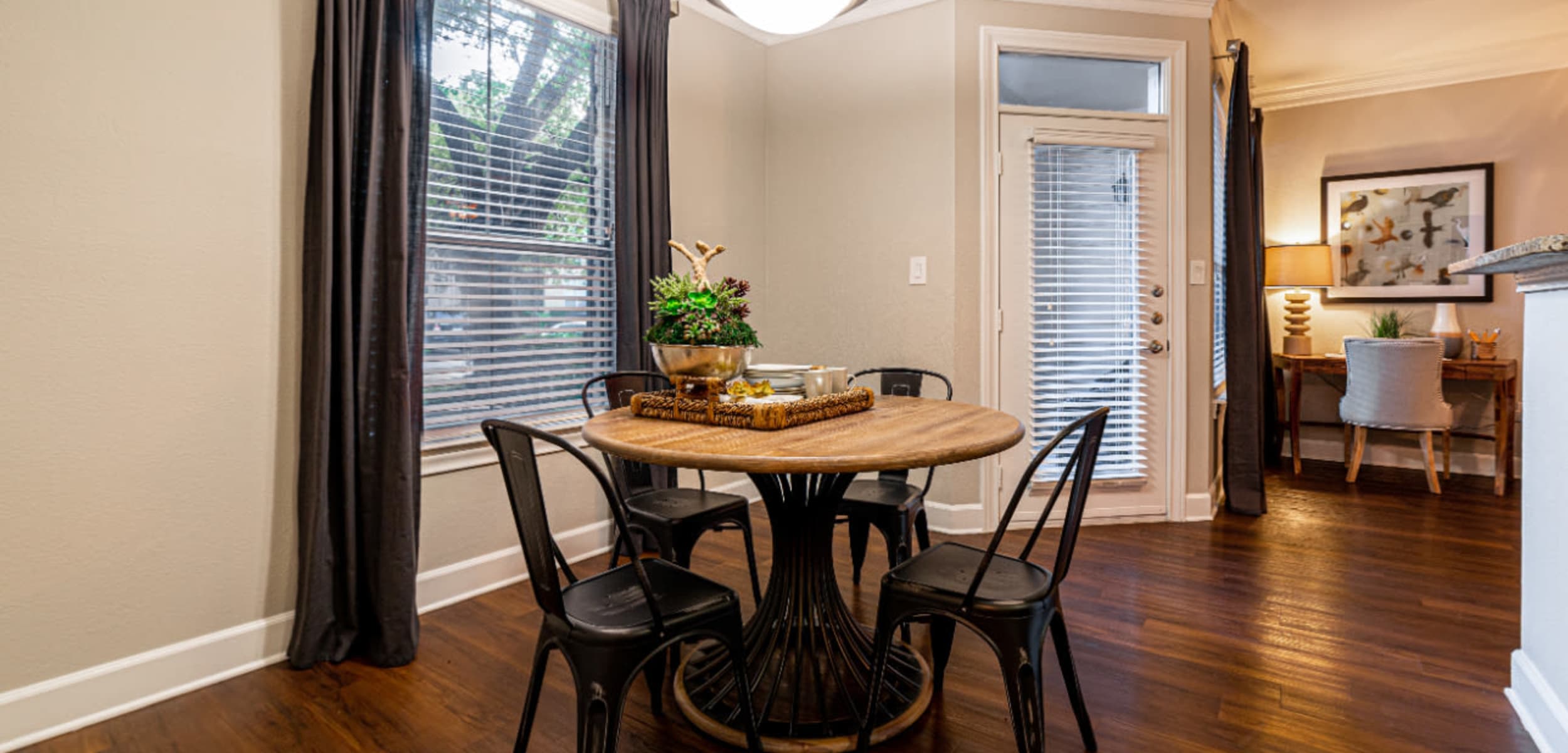 Dining table and chairs with large window and wood flooring at Marquis at Great Hills in Austin, Texas