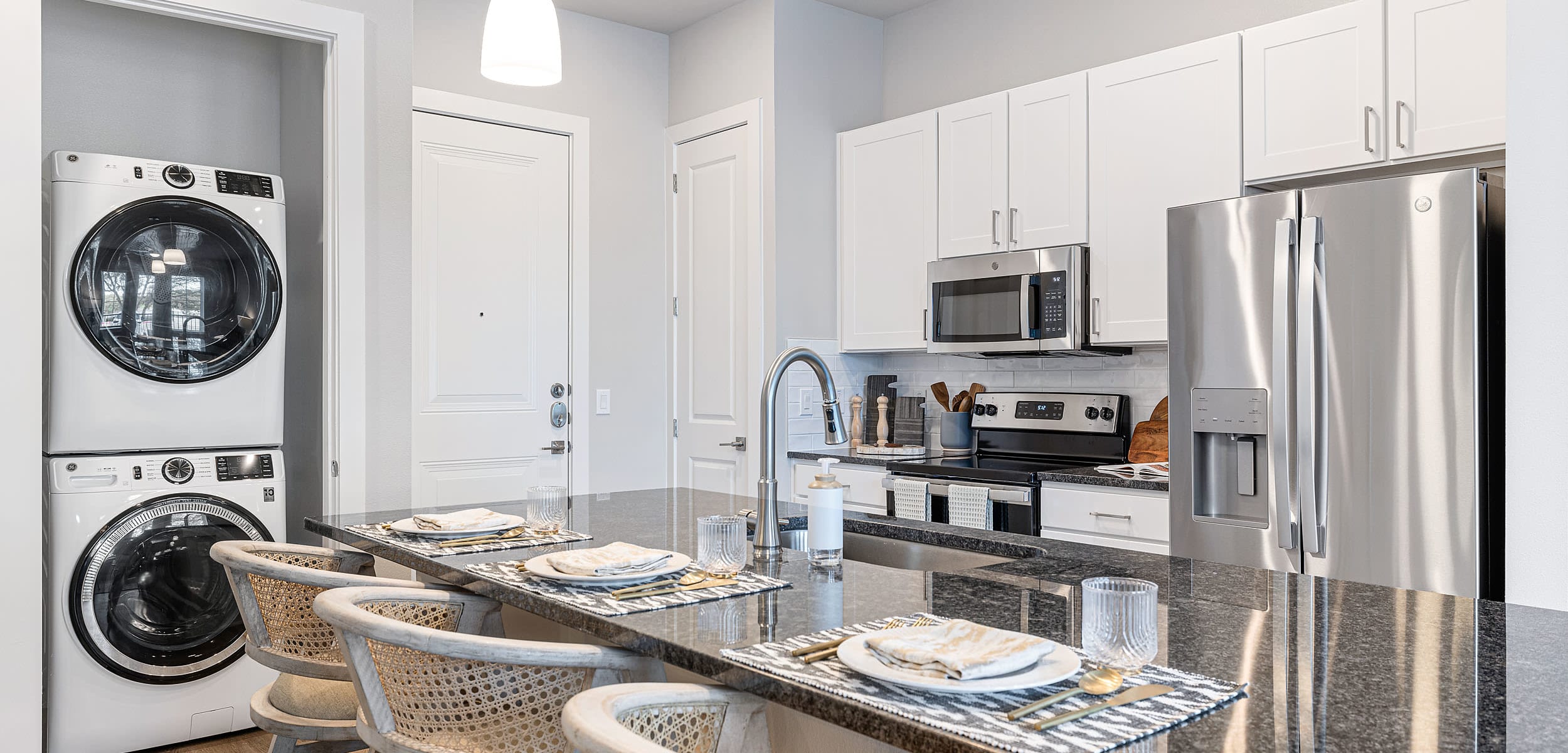 Model apartment kitchen featuring stainless steel appliances and breakfast bar seating at The Avery in Austin, Texas
