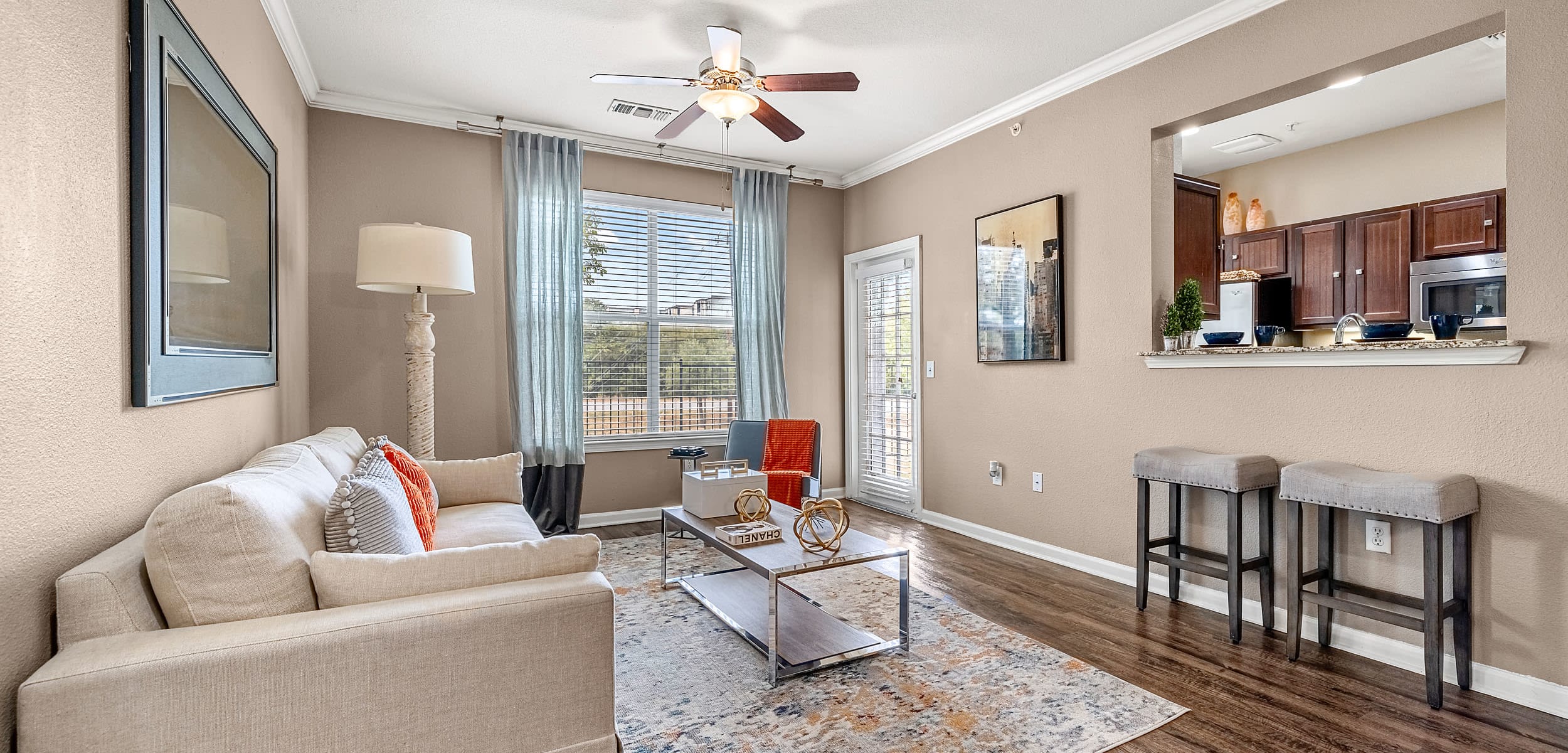 Open and bright living area with wood floors and a large rug at Marquis at Crown Ridge in San Antonio, Texas