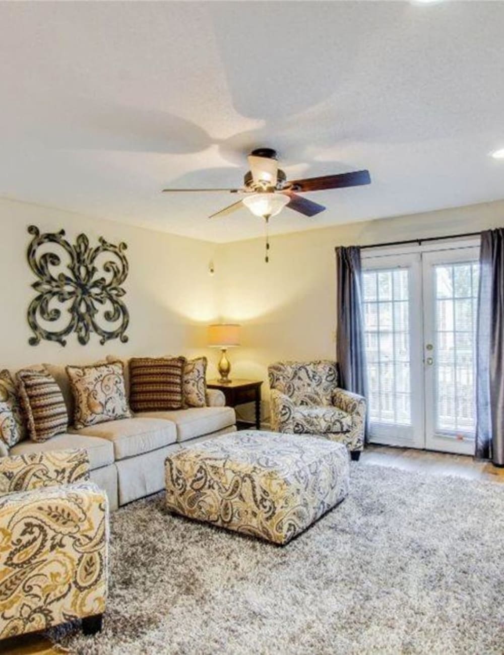 A spacious apartment living room with doors to the patio at The Gables in Ridgeland, Mississippi
