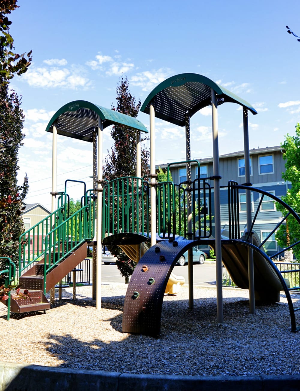 Green and brown playground outside at Heritage Meadow Apartments in Eugene, Oregon