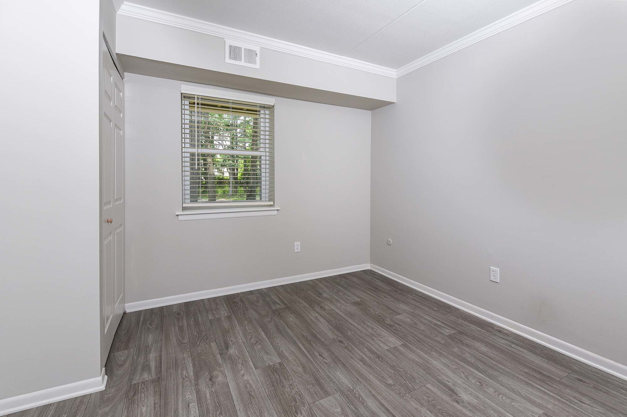 empty bedroom with gray walls dark hardwood like plank flooring at The Nolan, Morrisville, Pennsylvania