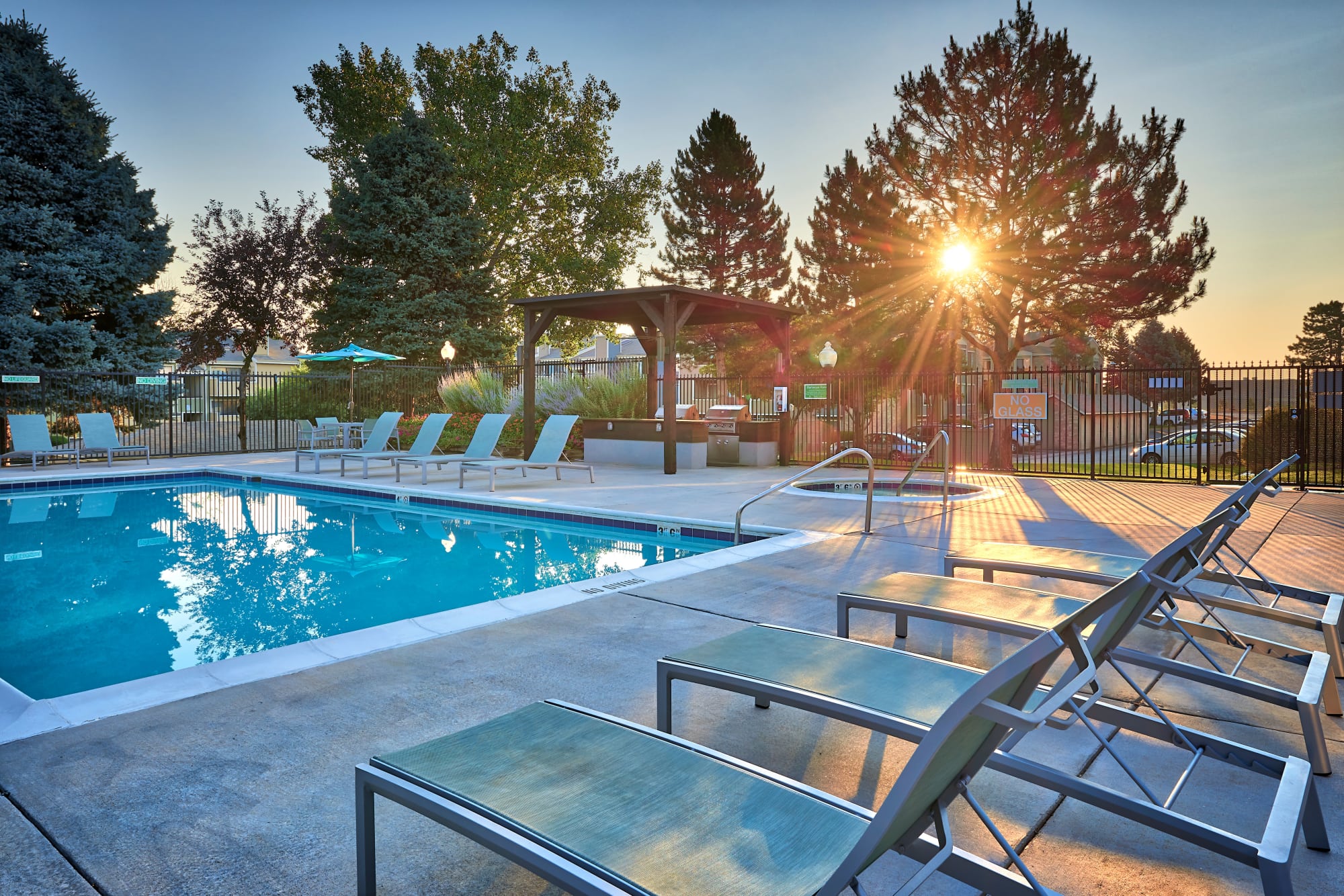 Swimming pool with lounge chairs at sunset at Alton Green Apartments in Denver, Colorado