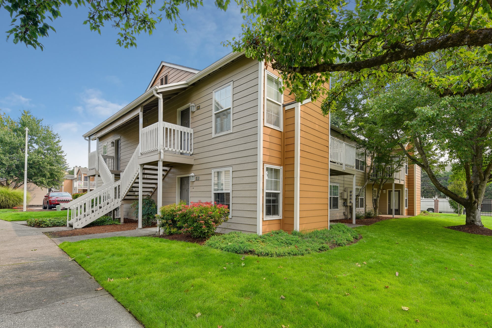 The exterior of the building surrounded by lush green grass at Carriage Park Apartments in Vancouver, Washington