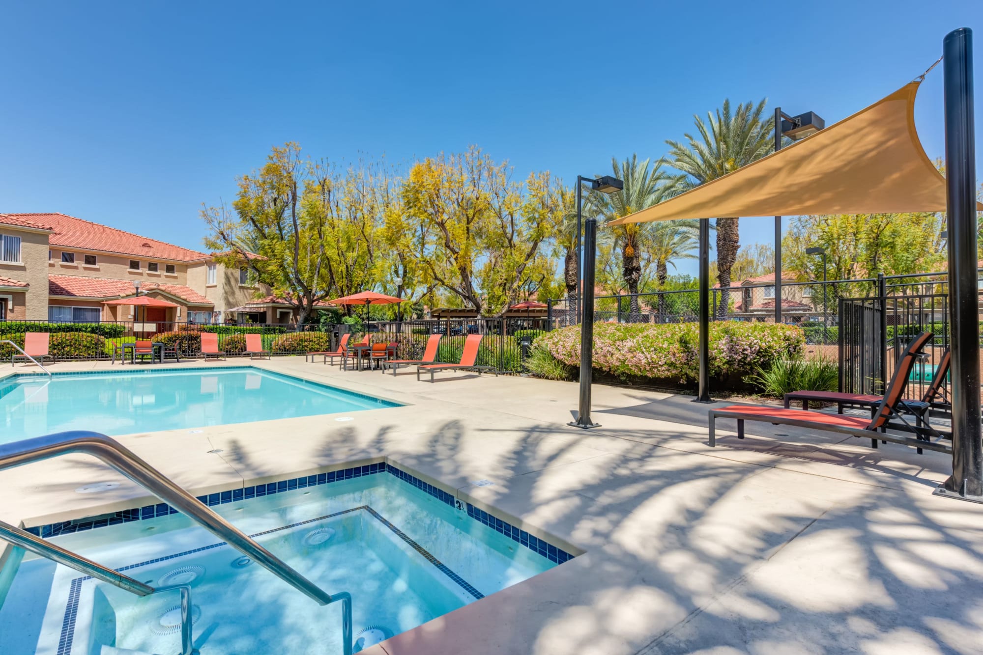 Spa and pool with lounge chairs and umbrellas at Tuscany Village Apartments in Ontario, California