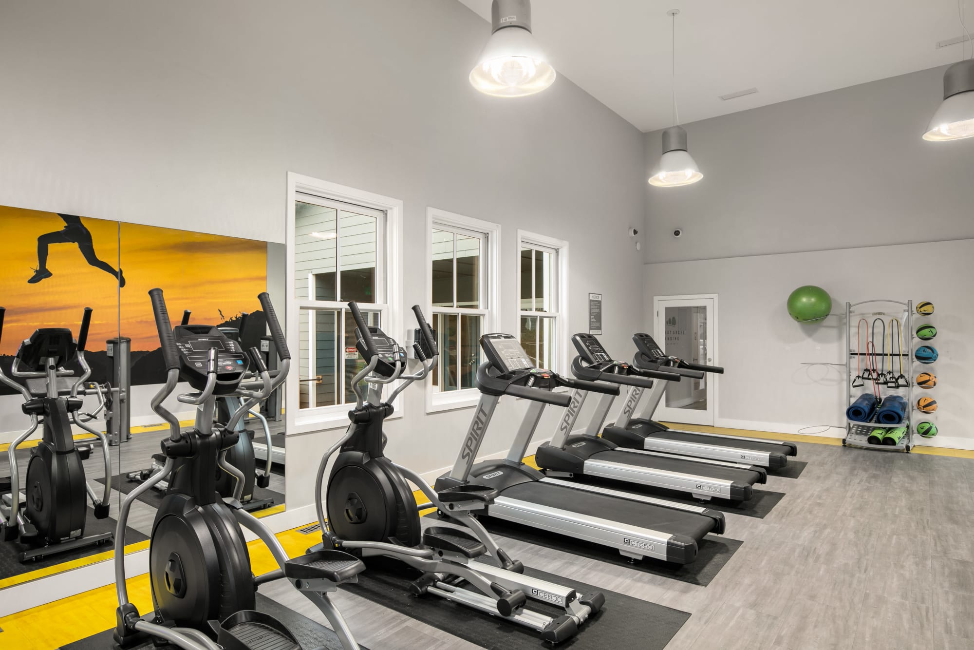 Fitness center with cardio machines and large windows looking out to the pool area at Walnut Grove Landing Apartments in Vancouver, Washington