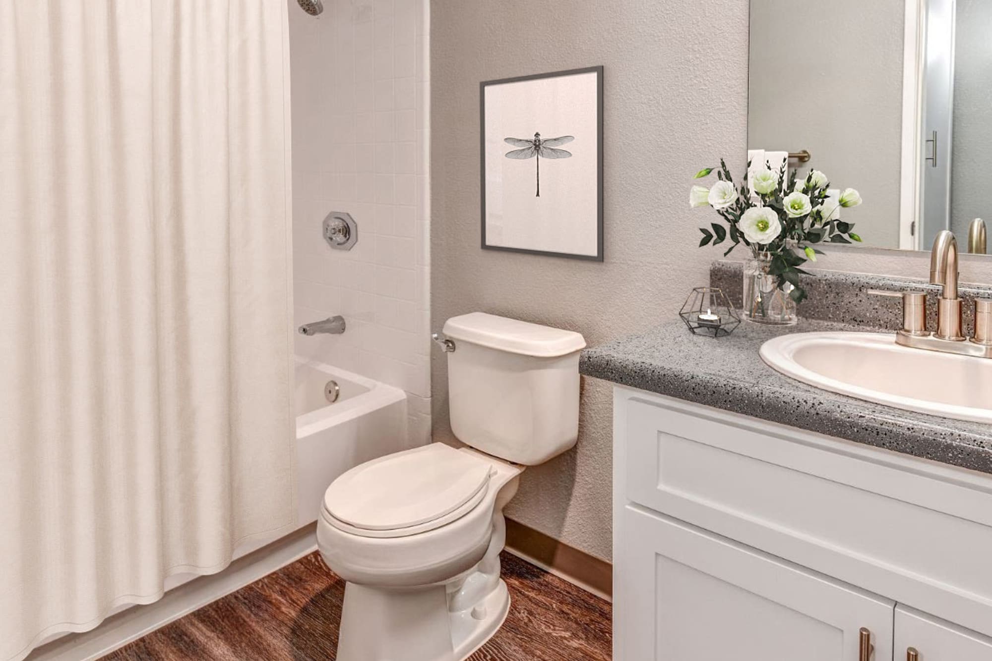 Bathroom with hardwood-style flooring at The Woodlands Apartments in Sacramento, California