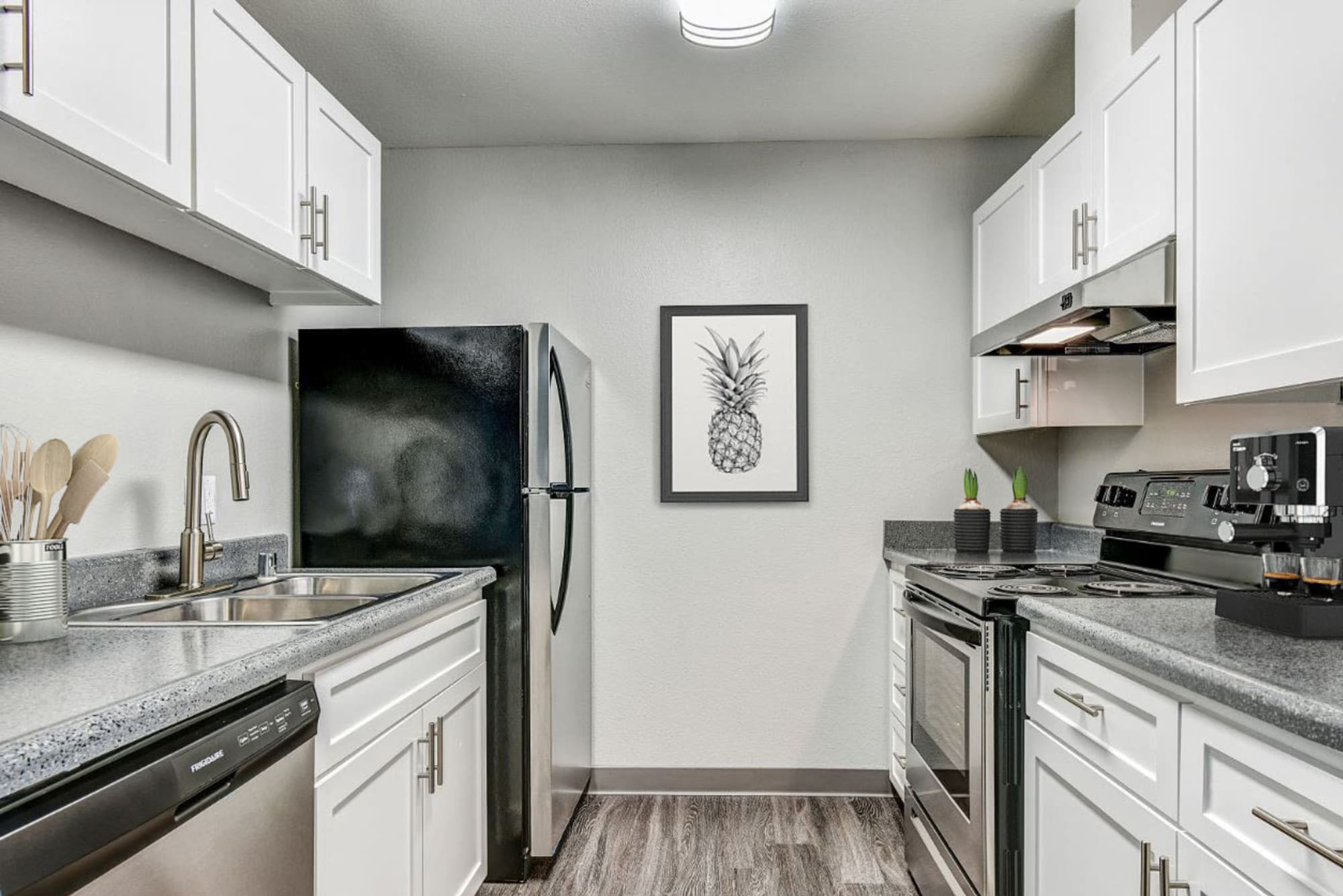 Newly renovated kitchen with white cabinets and stainless steel appliances at The Woodlands Apartments in Sacramento, California
