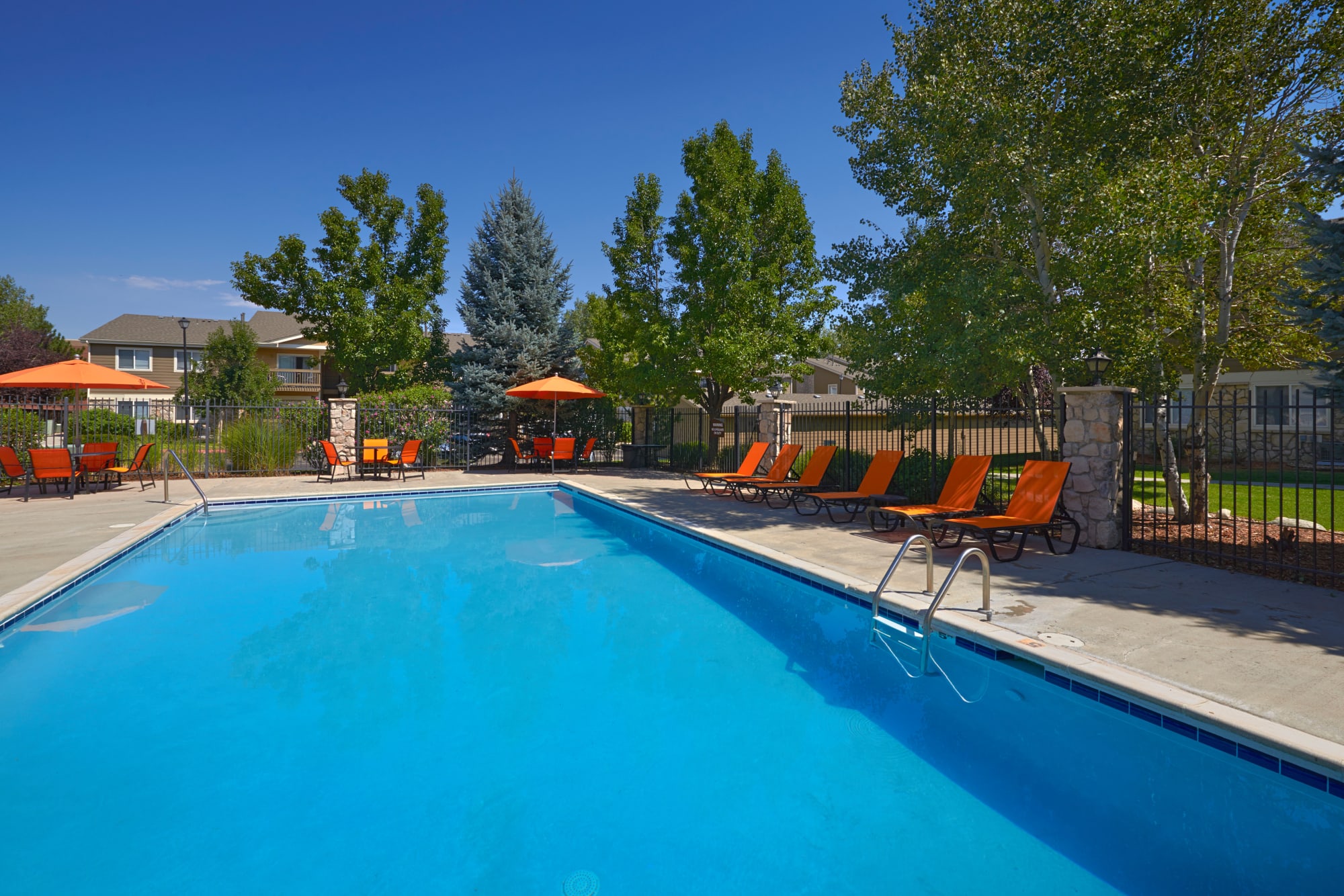 Pool with lounge chairs and umbrellas at Crossroads at City Center Apartments in Aurora, Colorado