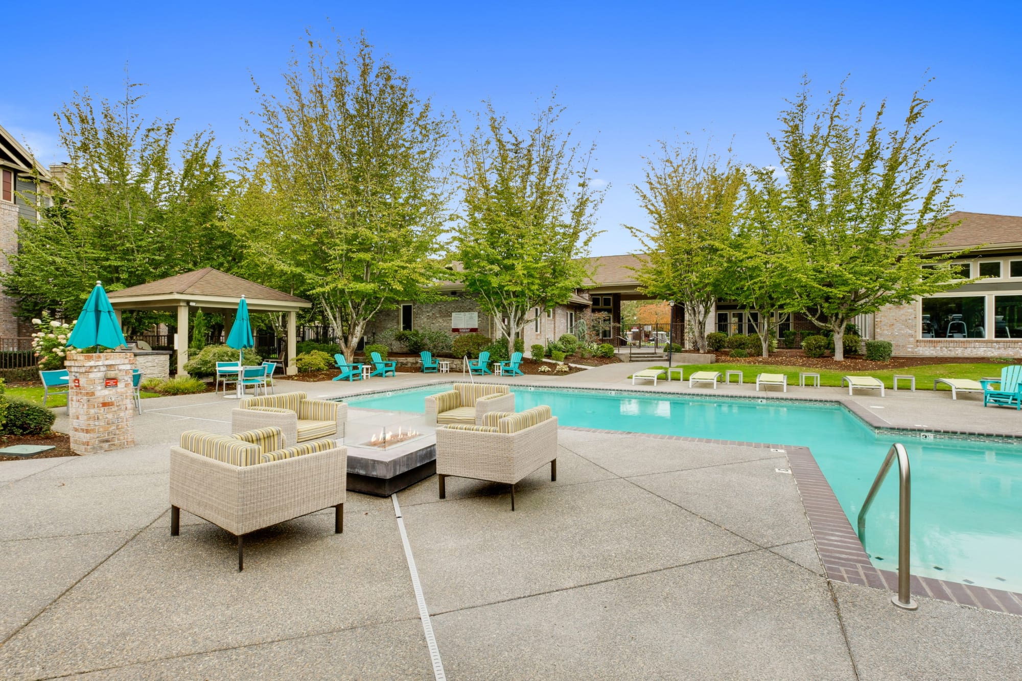 A fire pit surrounded by large chairs, poolside at The Grove at Orenco Station in Hillsboro, Oregon
