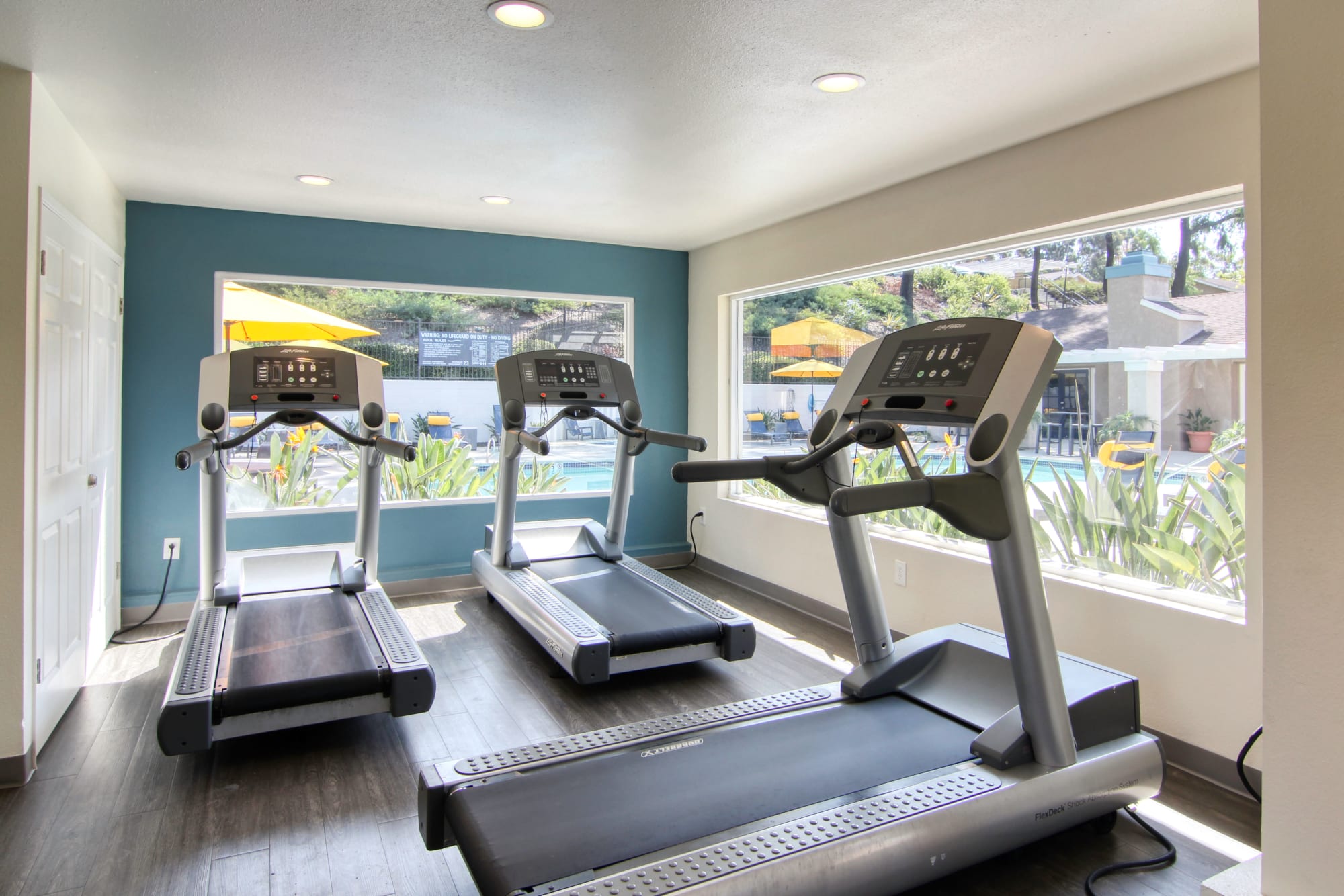 Newly renovated fitness center with large windows that look out to pool area at Lakeview Village Apartments in Spring Valley, California