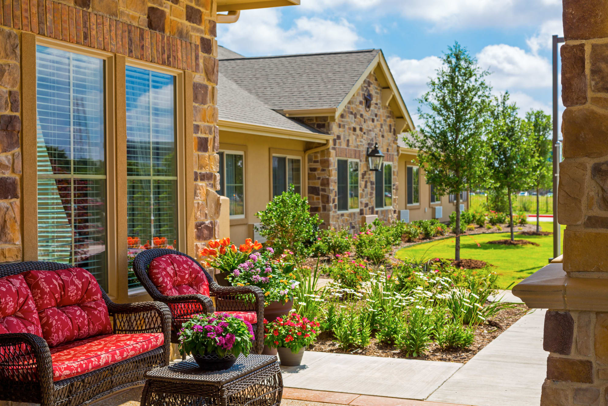 Apartment patio with wicker chairs at Saddlebrook Oxford Memory Care in Frisco, Texas