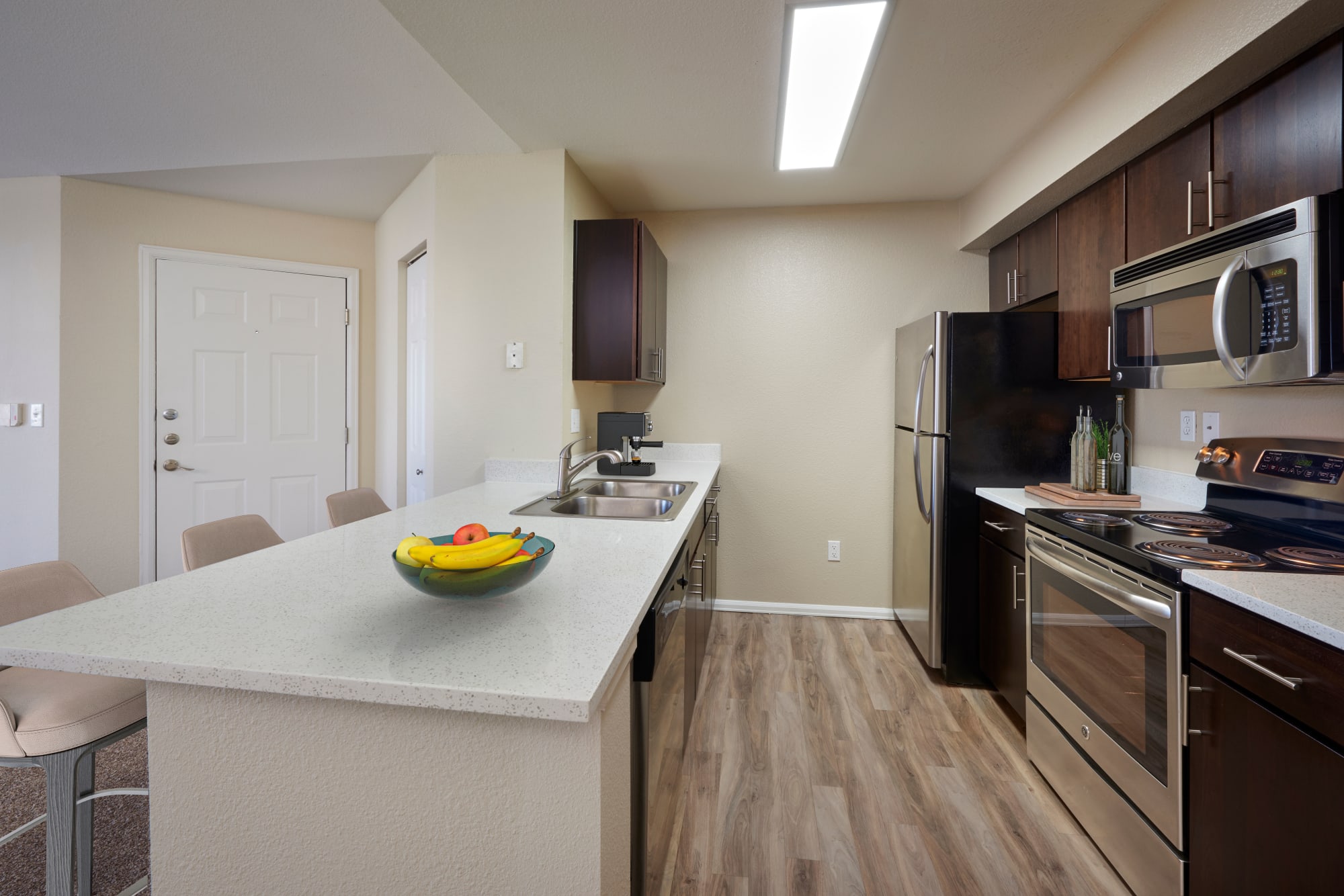 A renovated kitchen with brown cabinets and a breakfast bar at The Crossings at Bear Creek Apartments in Lakewood, Colorado