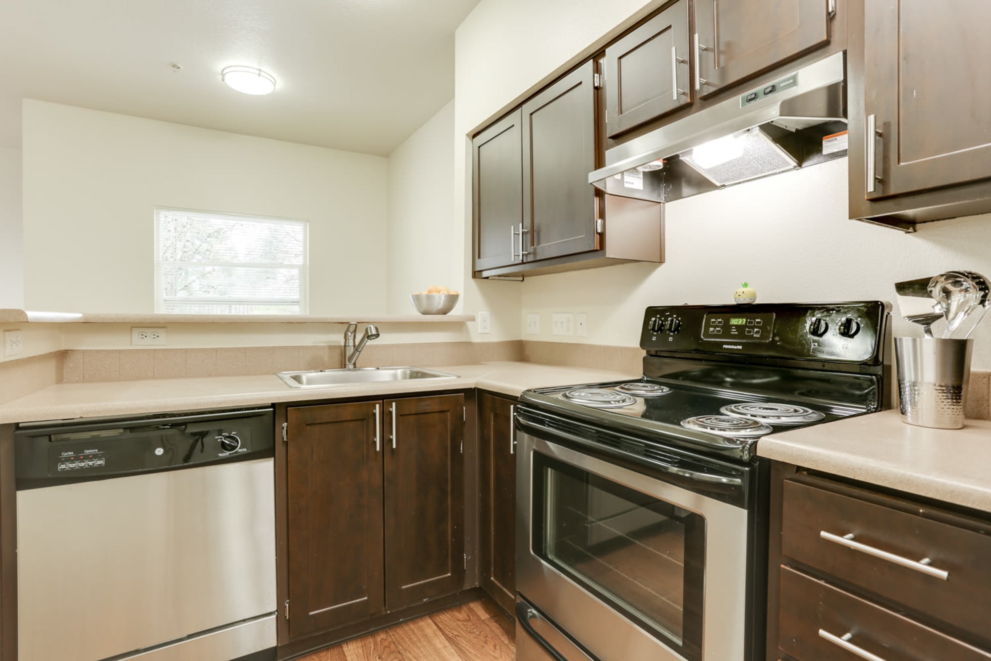 Newly renovated kitchen with brown cabinets and stainless steel appliances at The Landings at Morrison Apartments in Gresham, Oregon