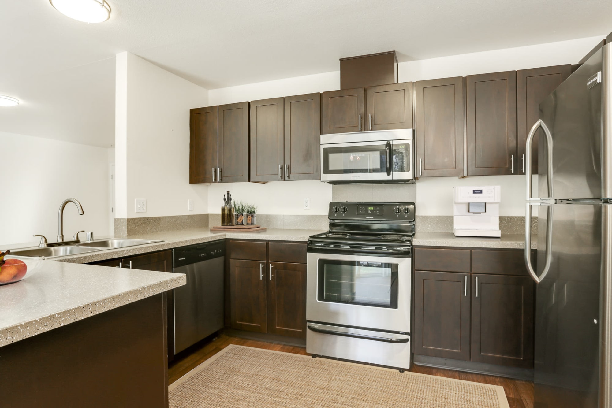 Renovated kitchen with brown cabinets and stainless steel appliances at The Addison Apartments in Vancouver, Washington