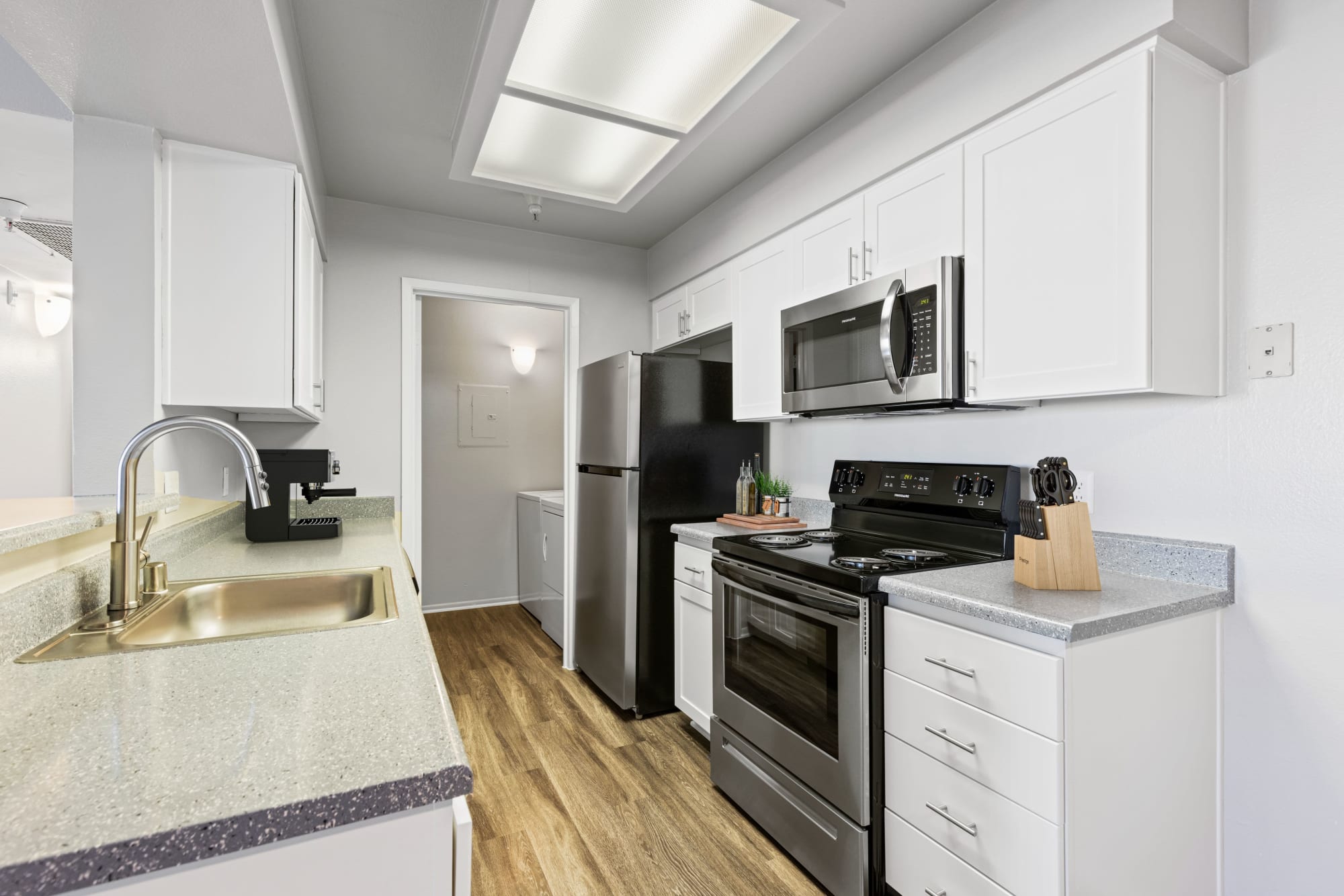 White renovated model kitchen with stainless steel appliances at Sierra Del Oro Apartments in Corona, California