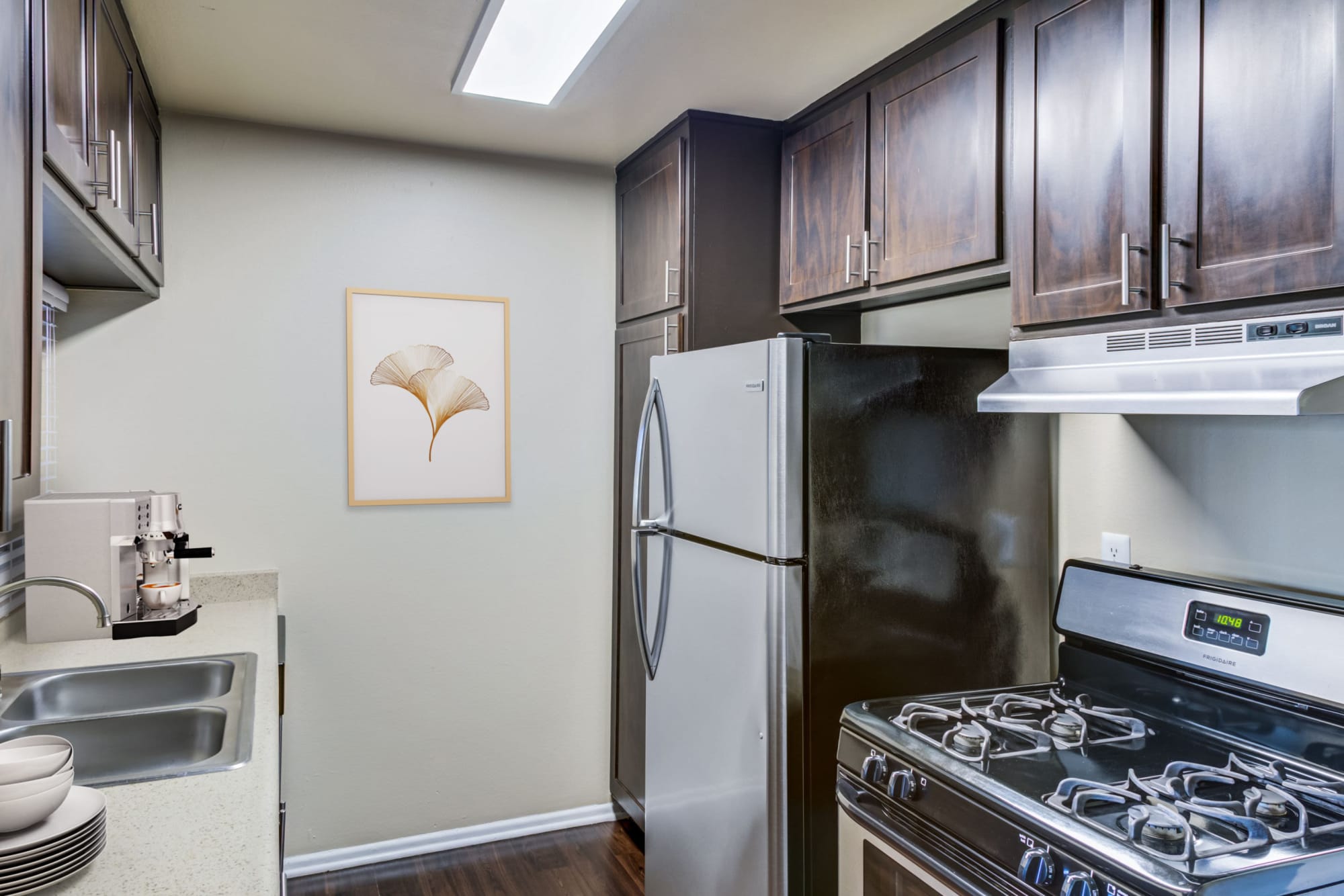 Renovated kitchen with brown cabinets and stainless steel appliances at Kendallwood Apartments in Whittier, California