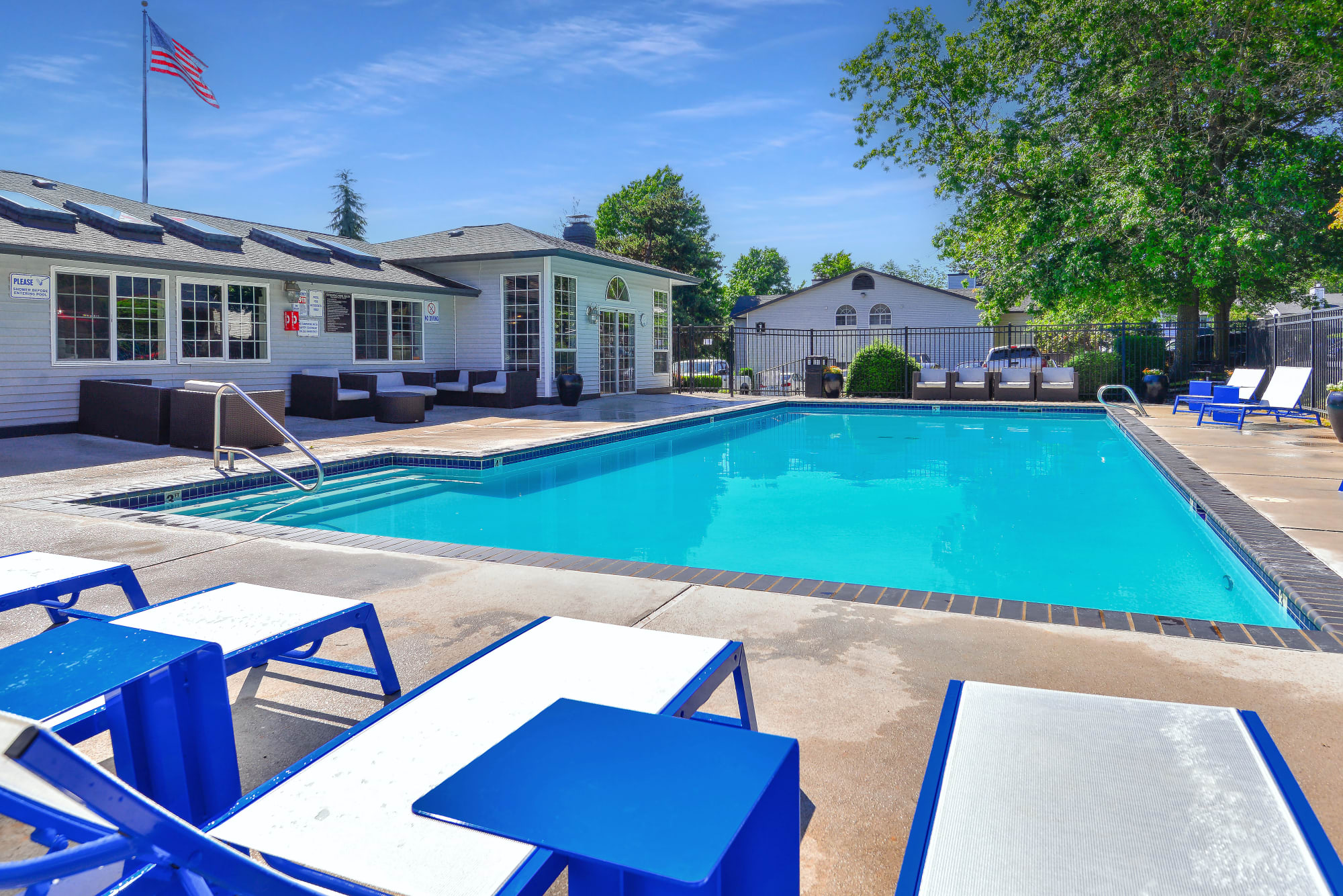 The inviting bright blue swimming pool with lounges at Wellington Apartment Homes in Silverdale, Washington