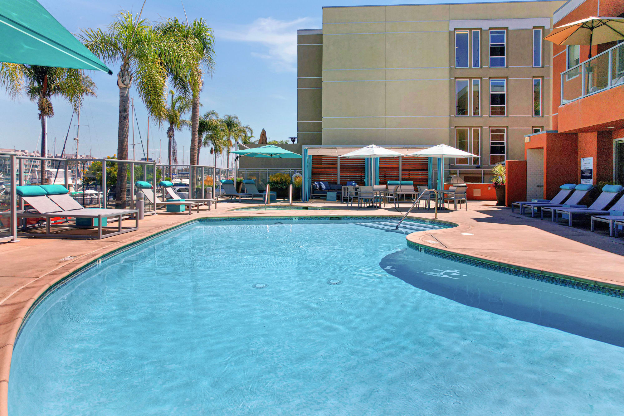 The pool and palm trees on a beautiful day at Harborside Marina Bay Apartments in Marina del Rey, California