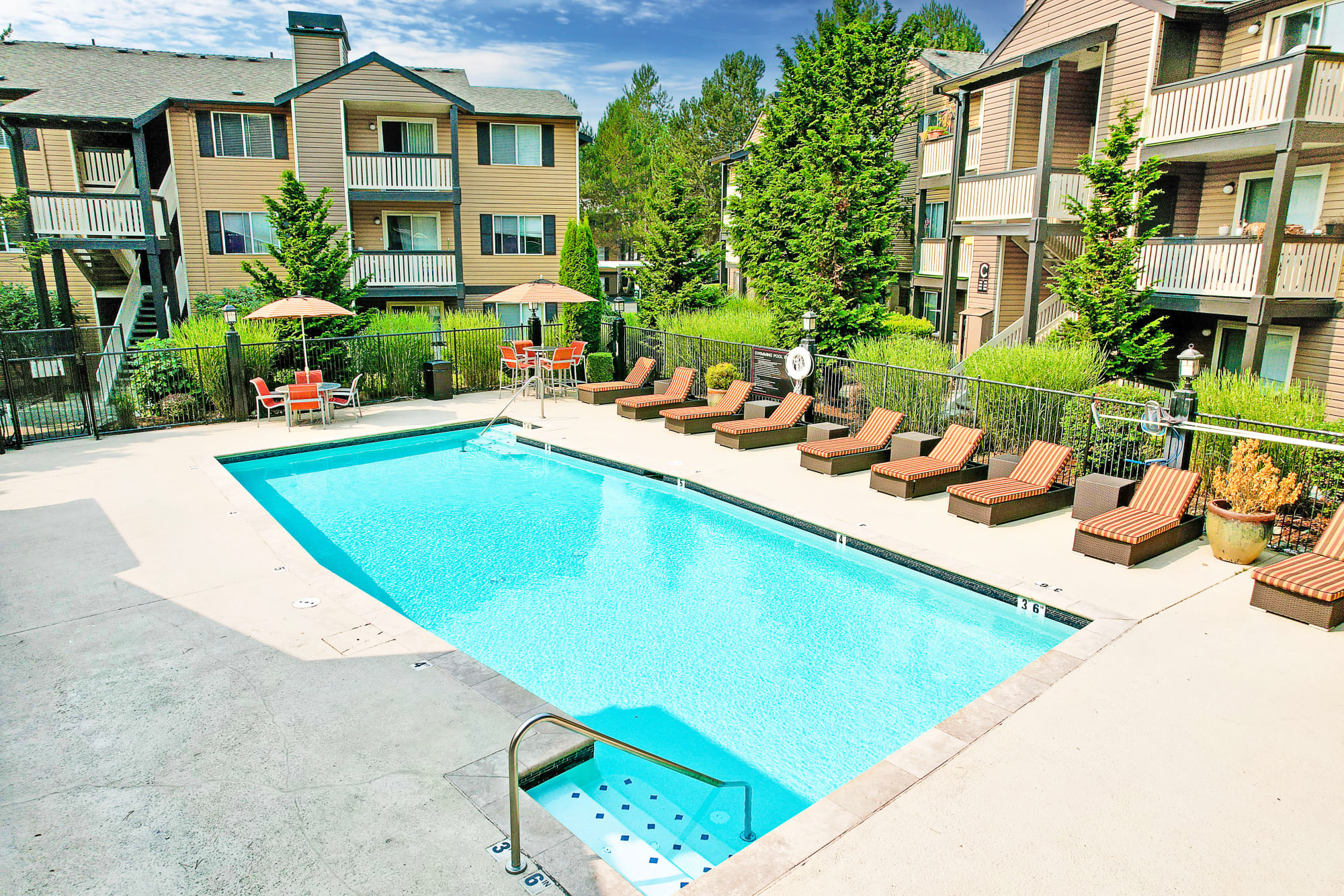 Aerial view of the pool, lounge chairs, leasing office, and landscaping at Newport Crossing Apartments in Newcastle, Washington