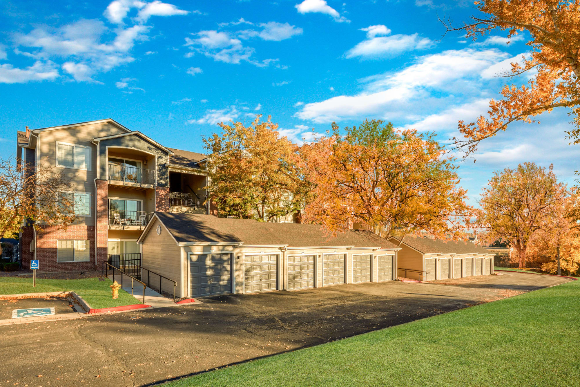The exterior of the building surrounded by lush landscaping at The Crossings at Bear Creek Apartments in Lakewood, Colorado