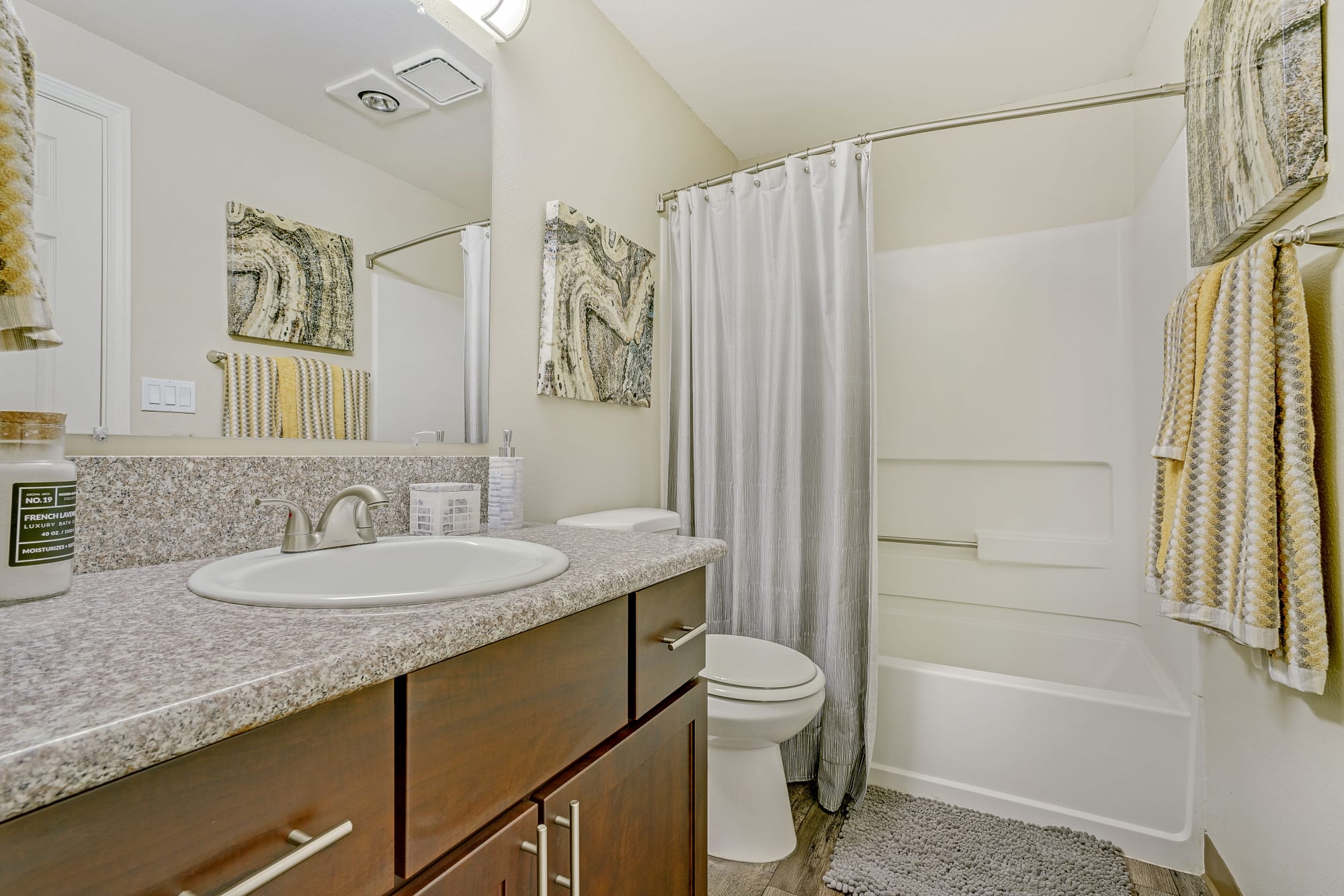 Renovated bathroom with brown cabinets and a tub at Walnut Grove Landing Apartments in Vancouver, Washington