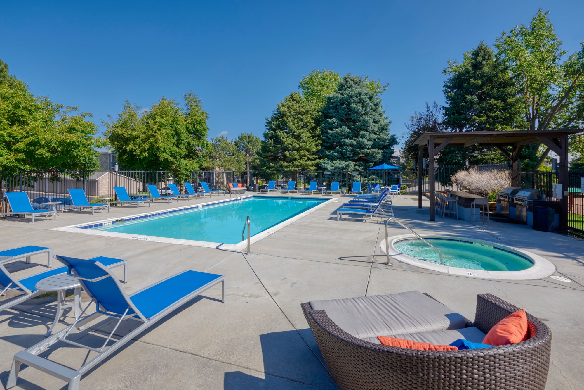 Swimming pool with lounge chairs at sunset at Alton Green Apartments in Denver, Colorado