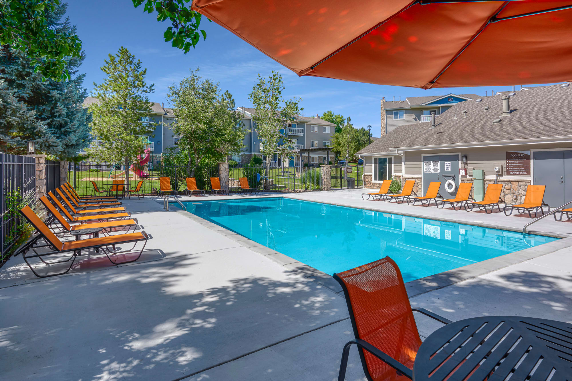 The pool surrounded by lush trees at Crossroads at City Center Apartments in Aurora, Colorado