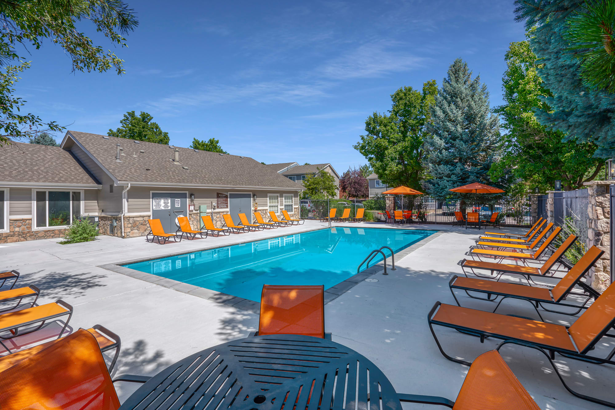 Pool with lounge chairs and umbrellas at Crossroads at City Center Apartments in Aurora, Colorado