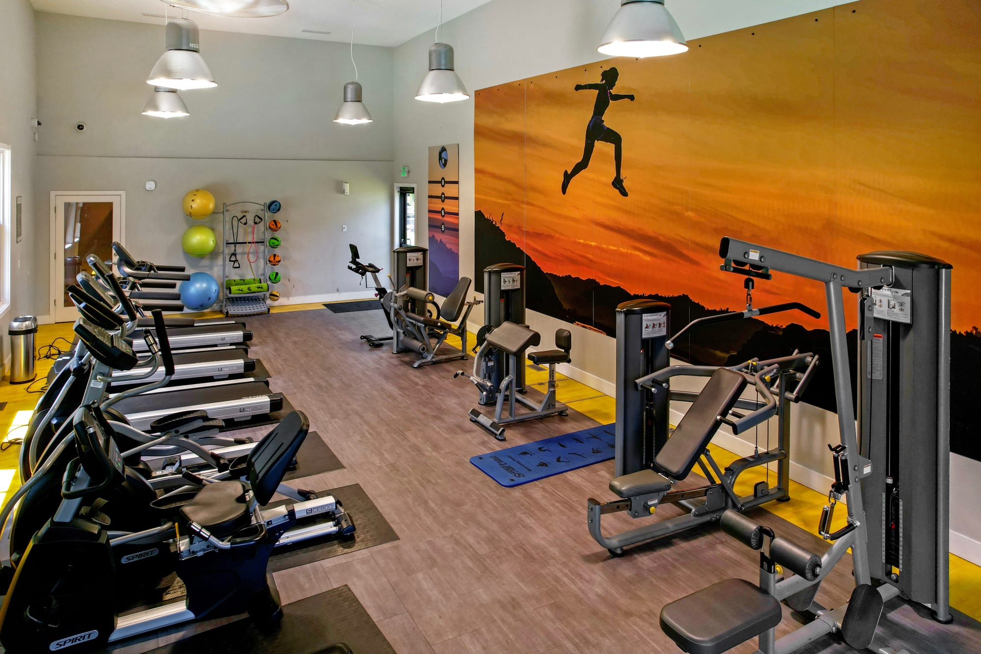 Fitness center with cardio machines and large windows looking out to the pool area at Walnut Grove Landing Apartments in Vancouver, Washington