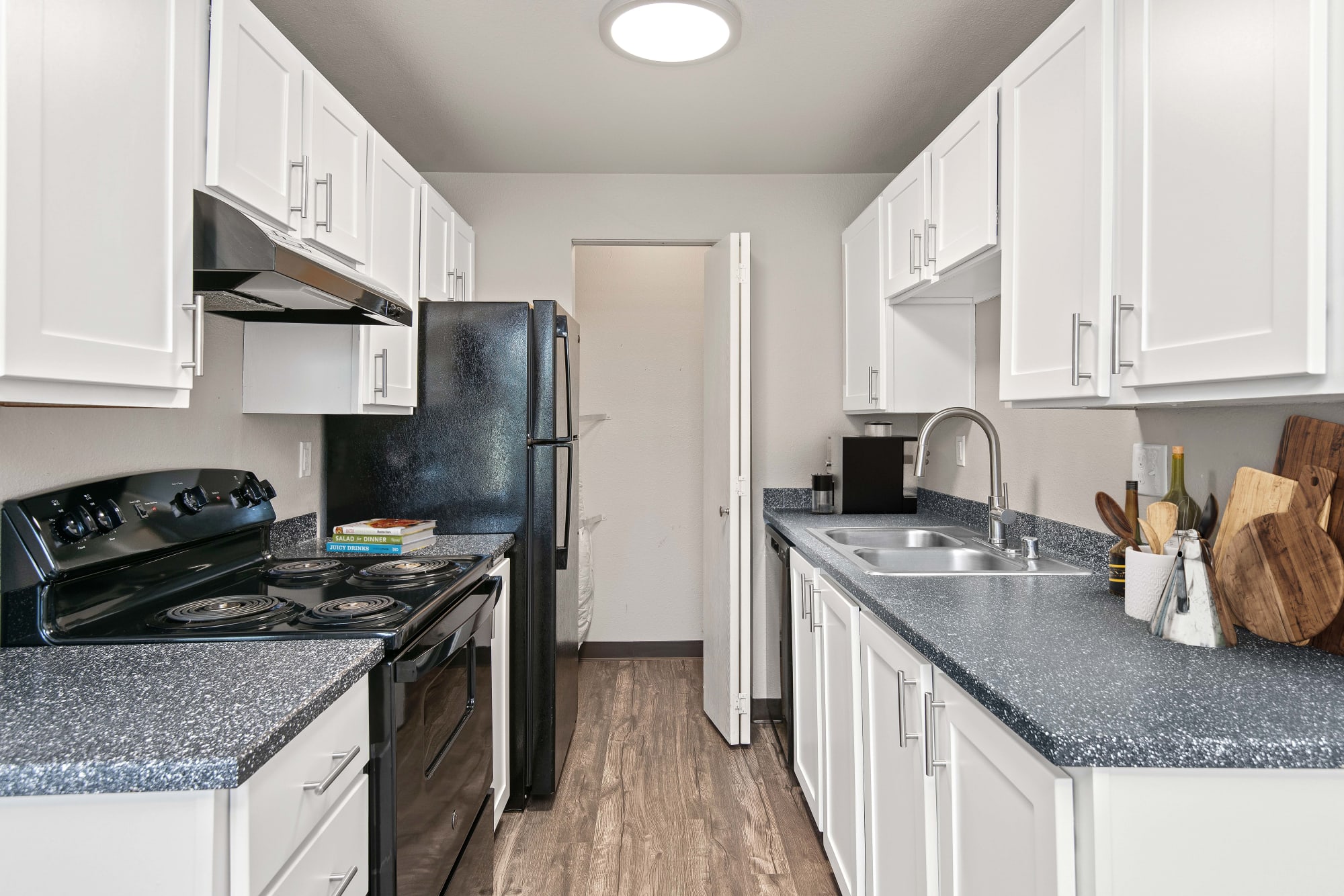 A spacious kitchen with hardwood-style flooring and renovated white cabinets at Wellington Apartment Homes in Silverdale, Washington